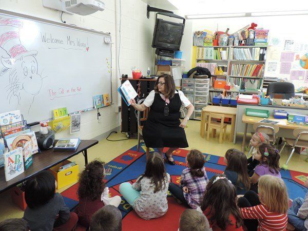 A woman is reading a book to a group of children in a classroom.