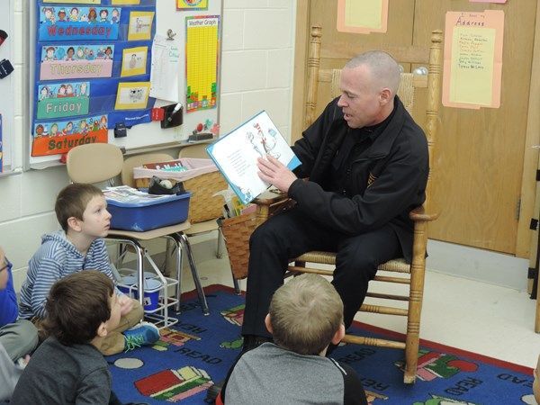 A man is reading a book to a group of children