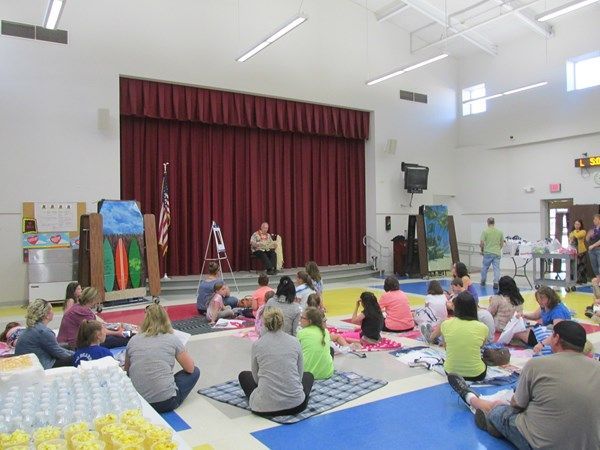 A group of people are sitting on the floor in front of a stage.