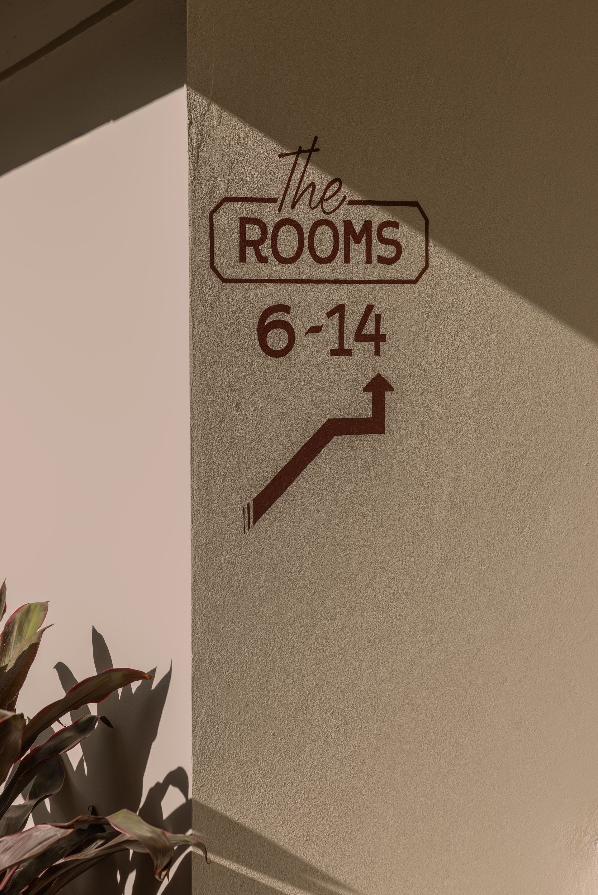 “The Rooms” room sign on a beige wall, marked 6–14 with an arrow pointing right.