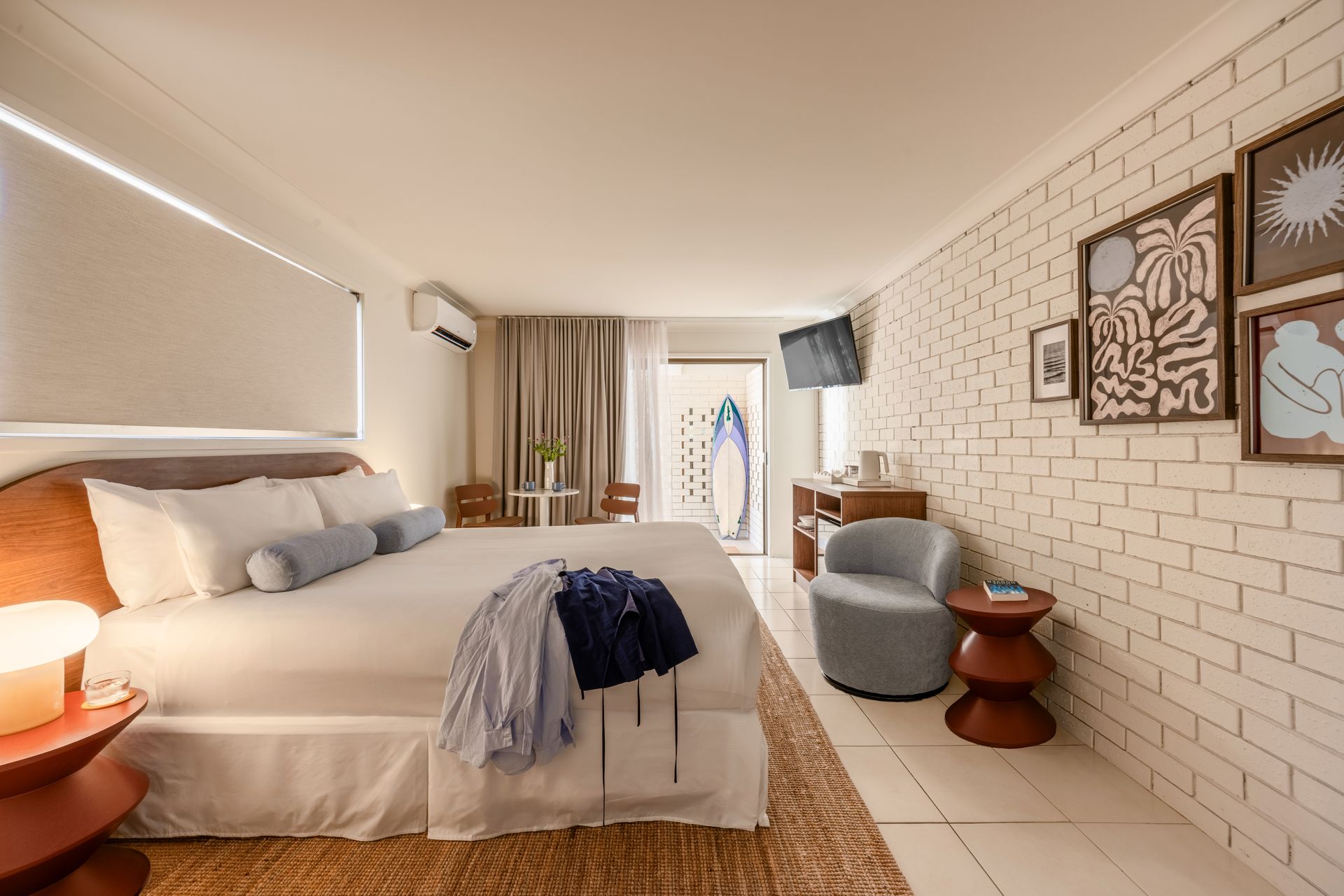Cozy bedroom with bed, warm lamps, woven rug, and brick accent wall