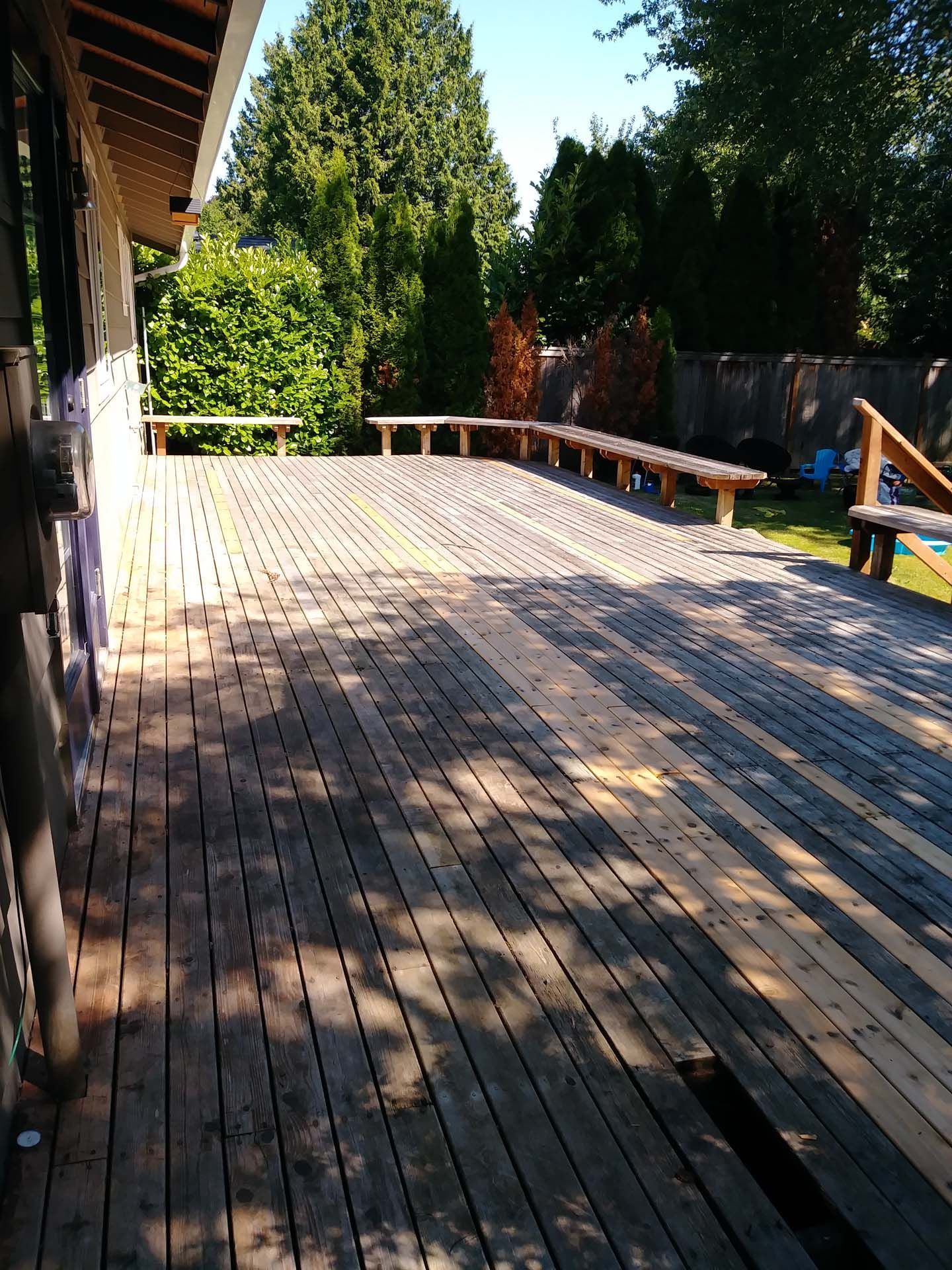 A large wooden deck with benches and trees in the background