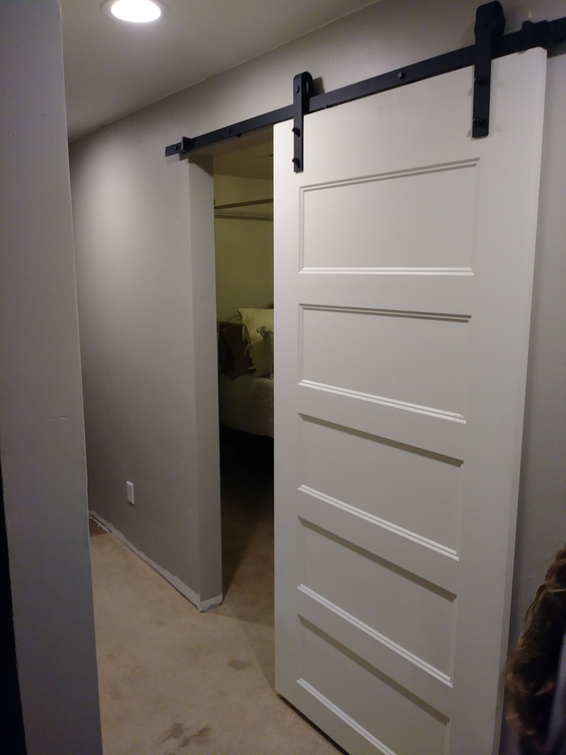 A white sliding barn door is open to a bedroom.