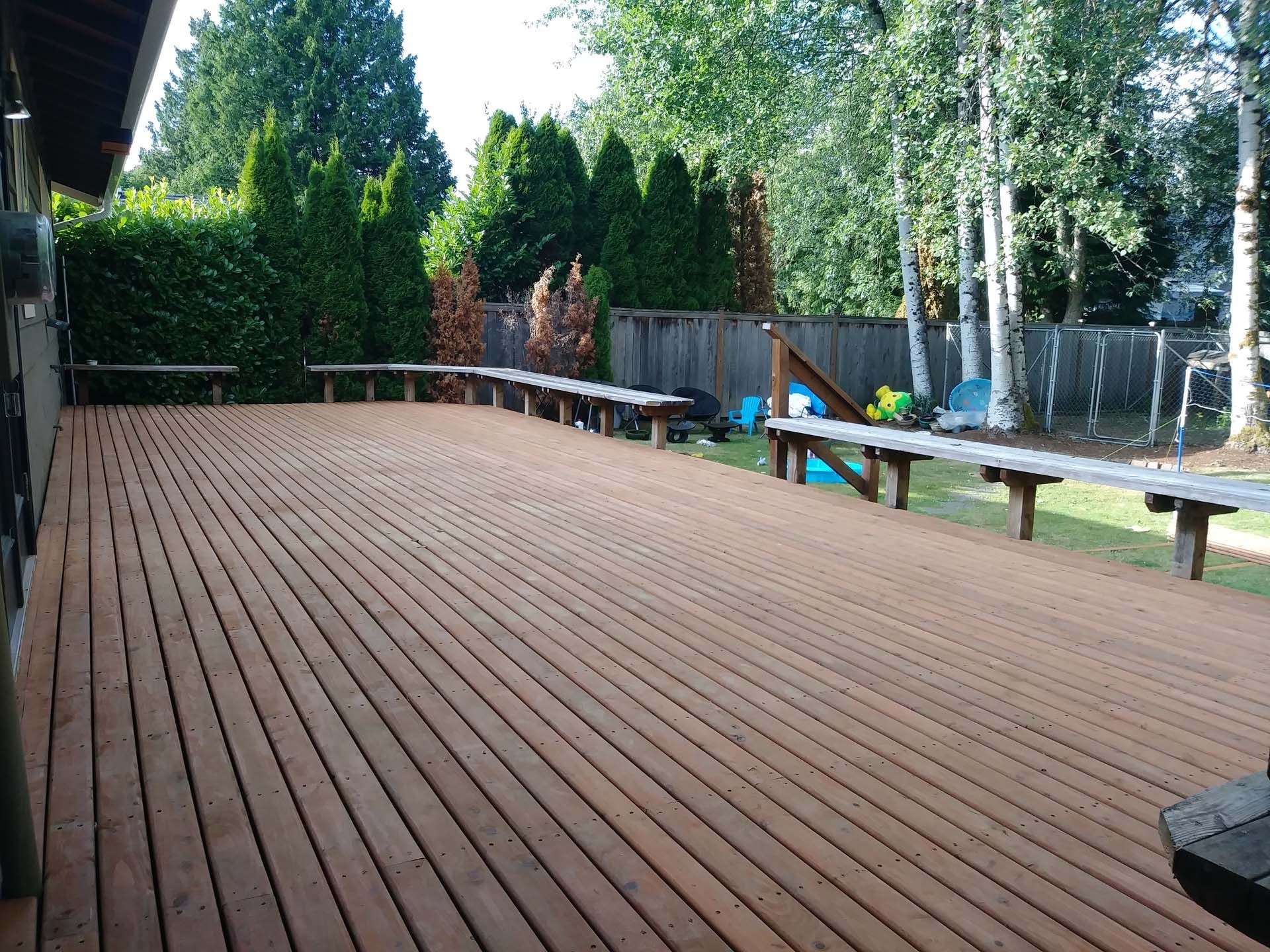 A large wooden deck with benches and trees in the background