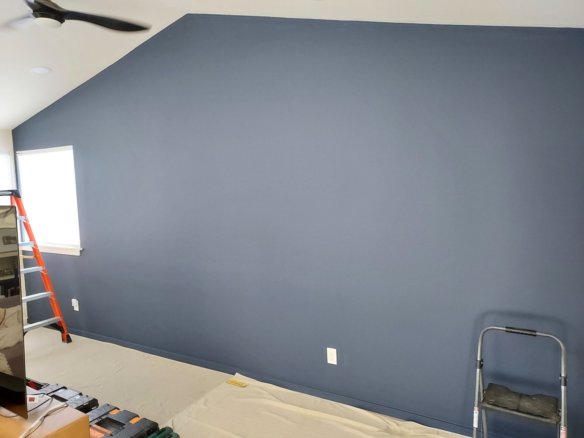A living room with a blue wall and a ladder.