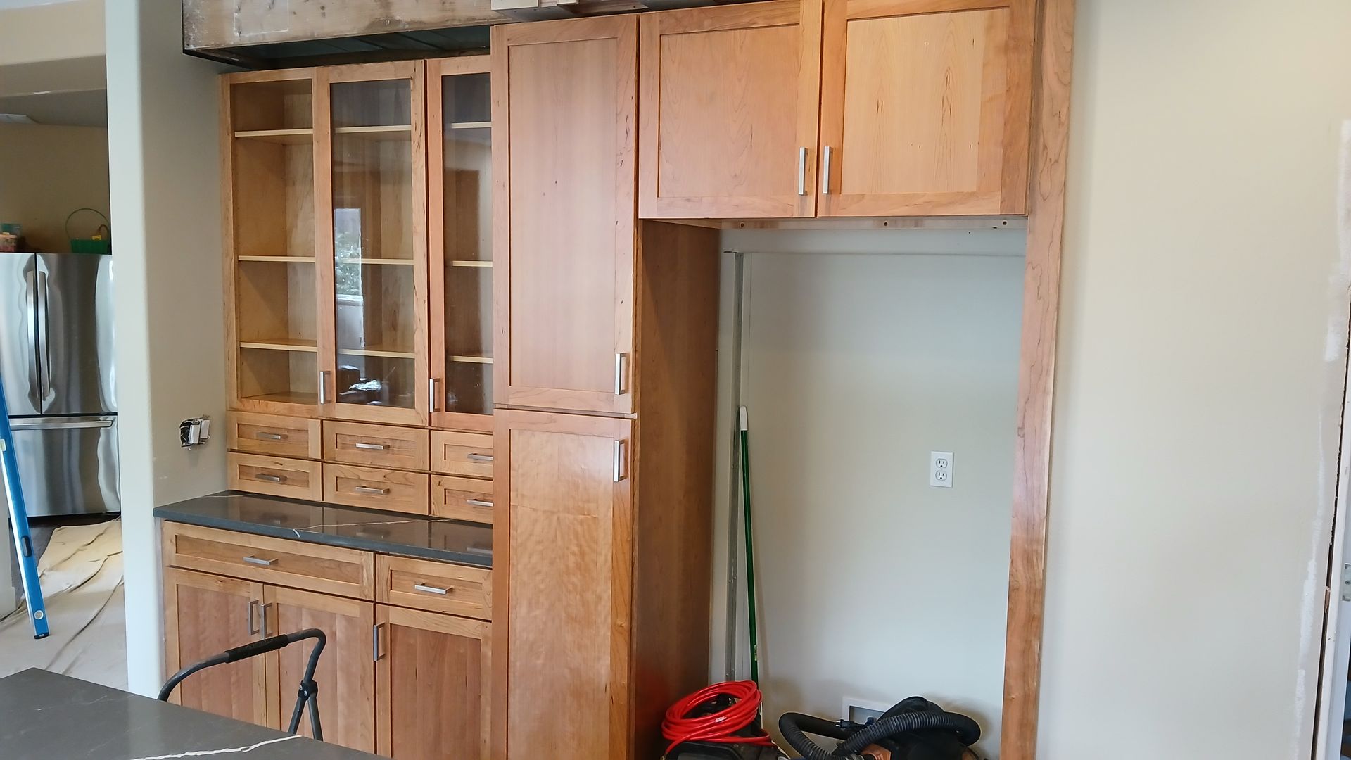 A kitchen with wooden cabinets and a ladder in the background.