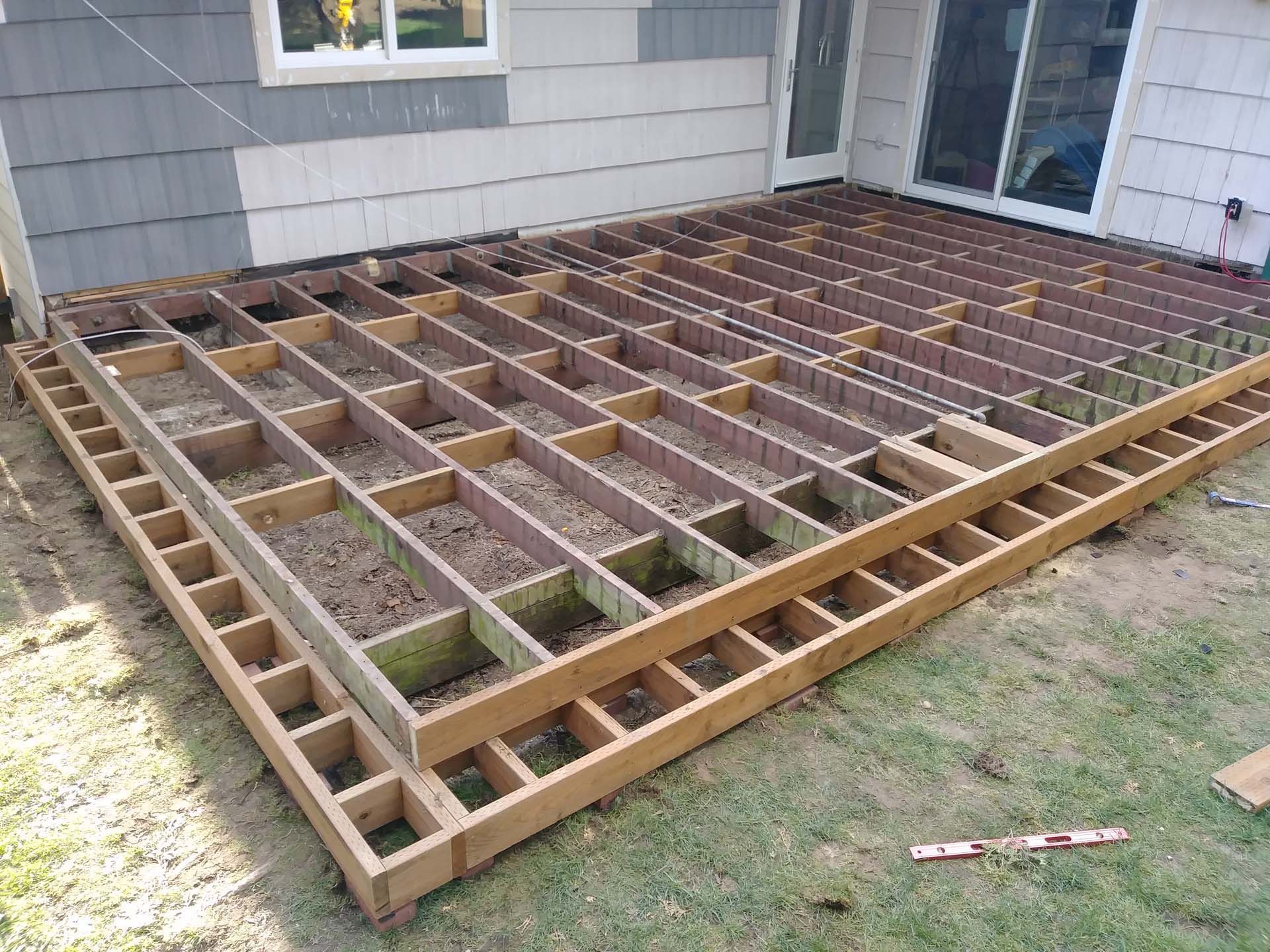 A wooden deck is being built in front of a house.
