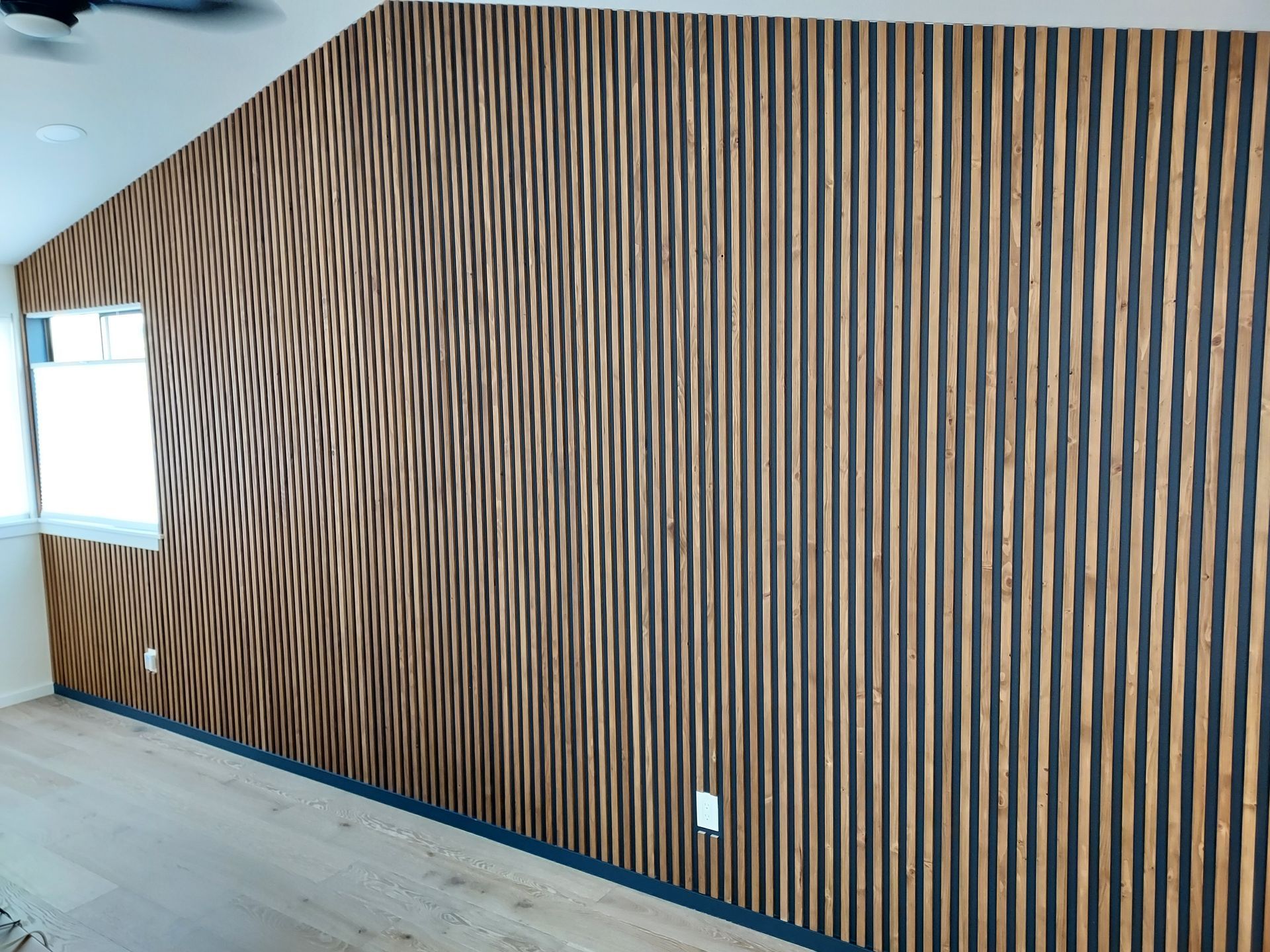 A room with a wooden wall and a ceiling fan.