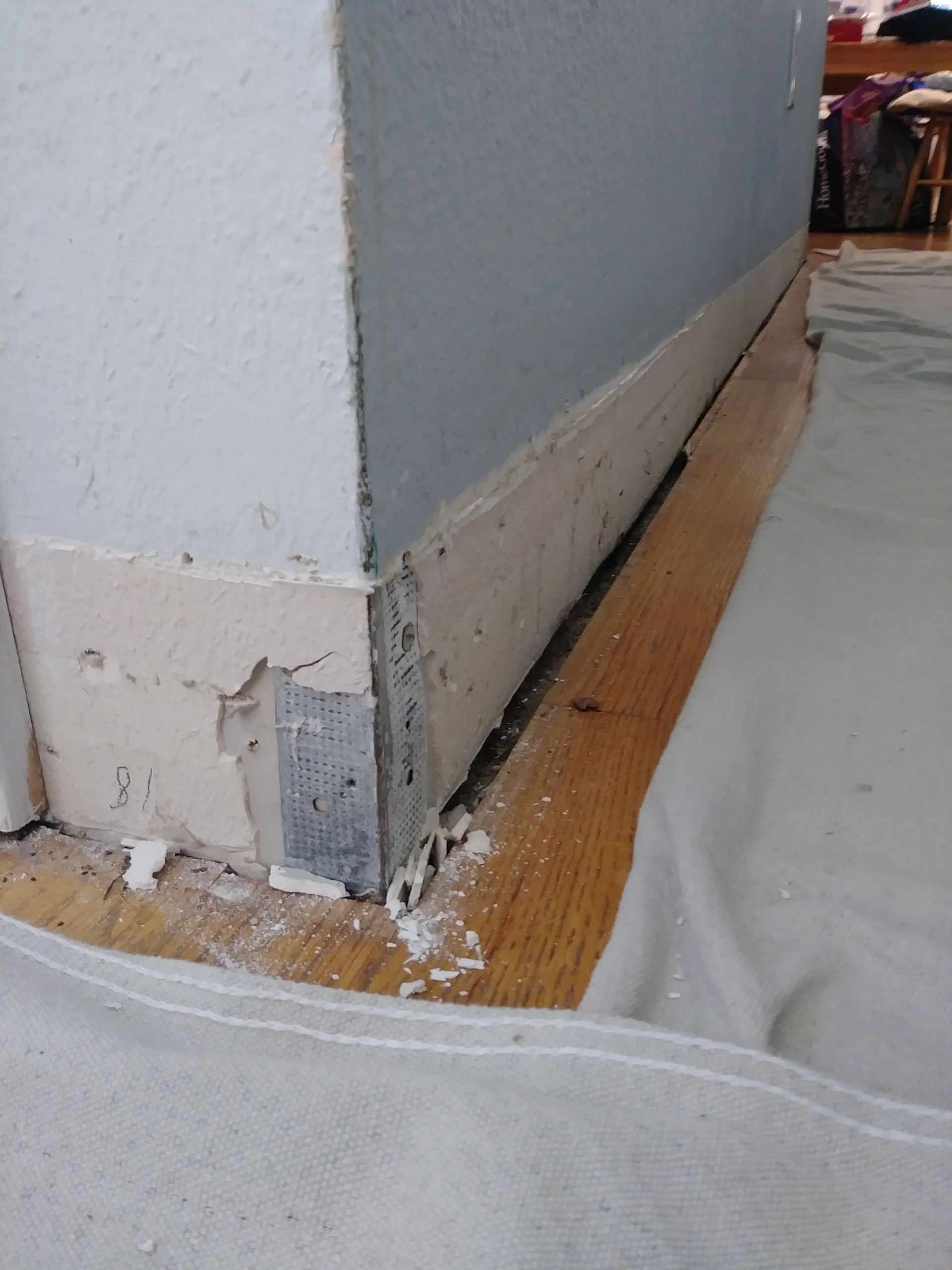 A corner of a room with a gray wall and a wooden floor