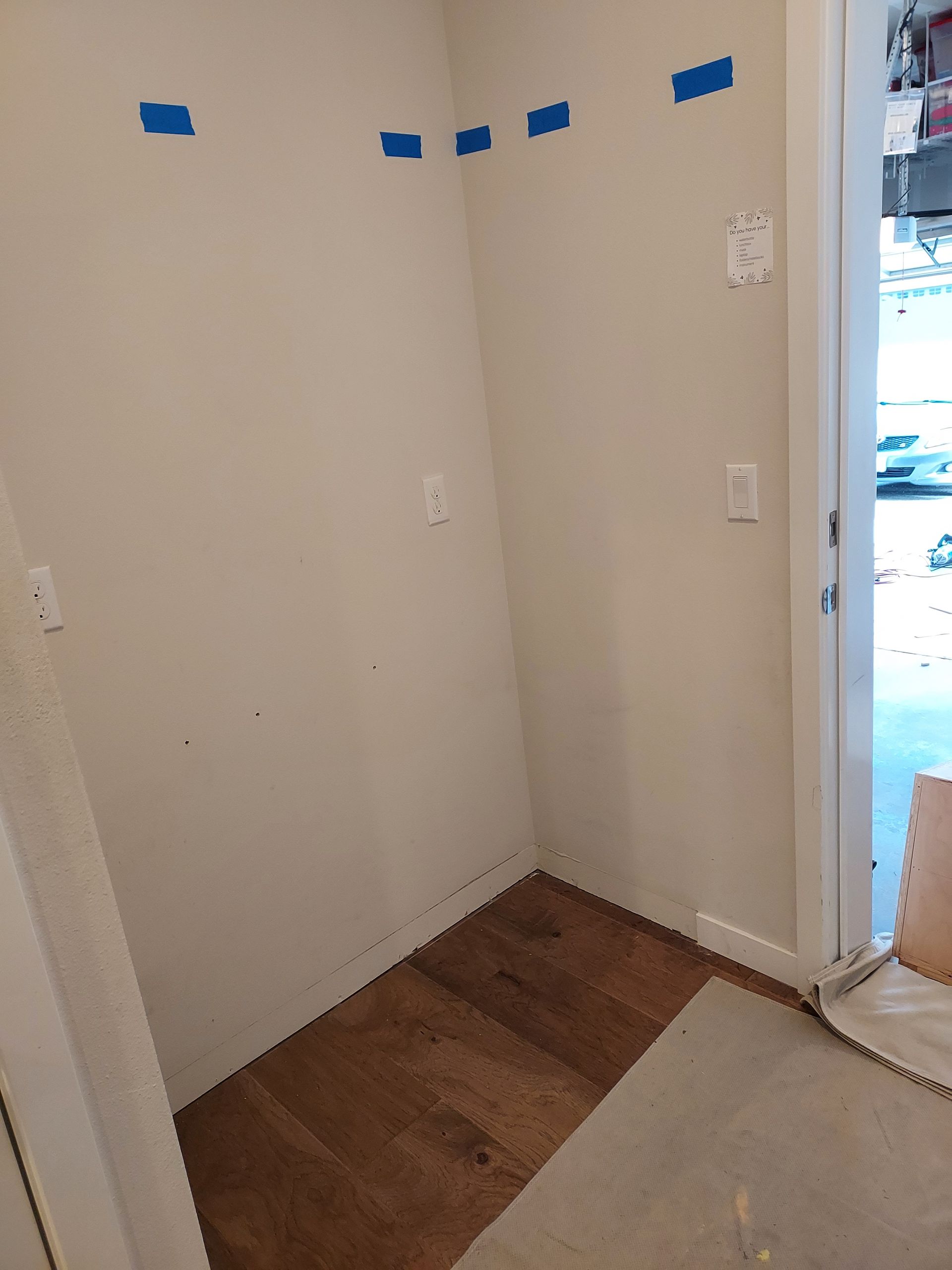 A corner of a room with a door and tape on the wall.