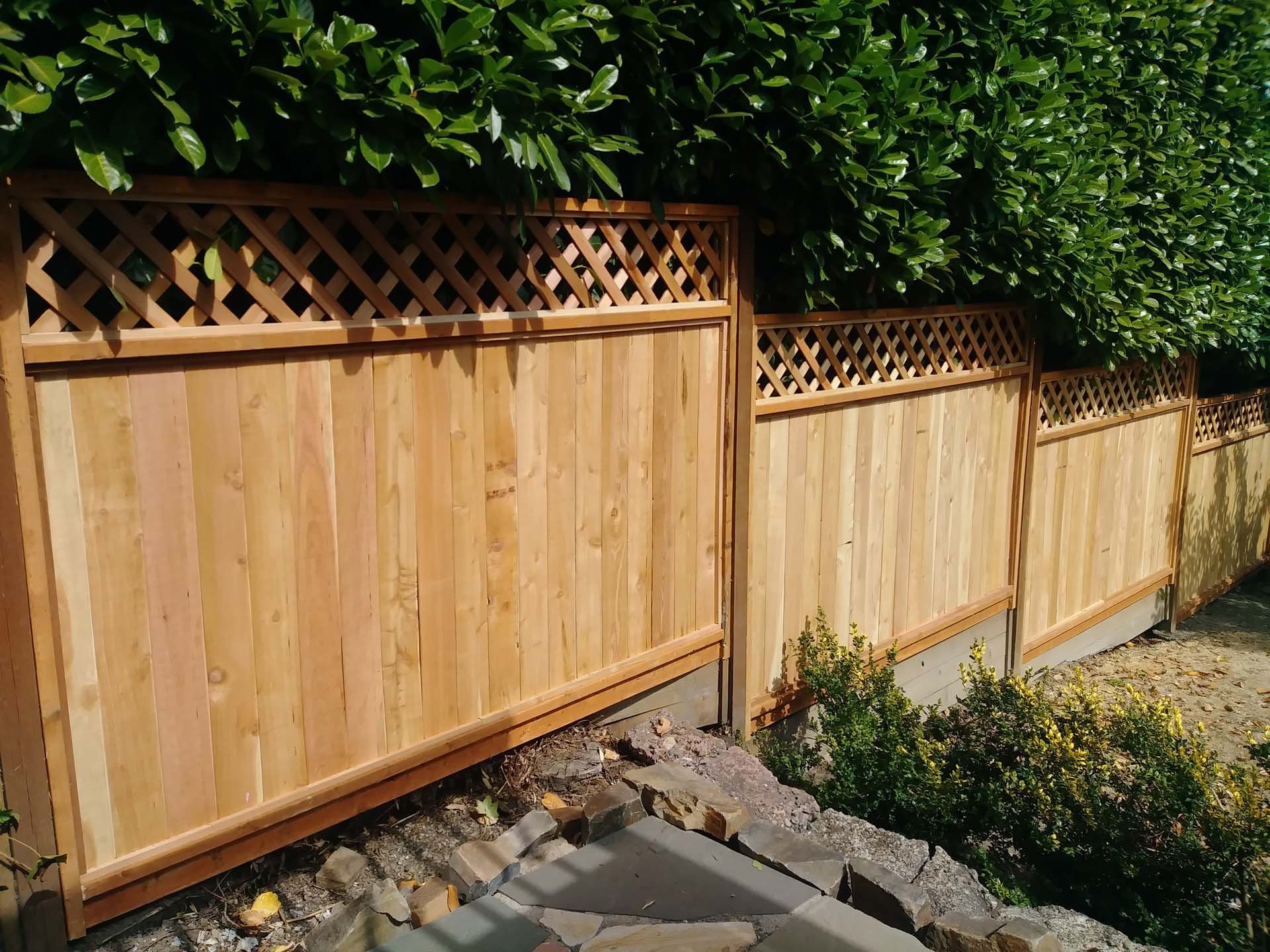 A wooden fence with a lattice design is surrounded by trees.