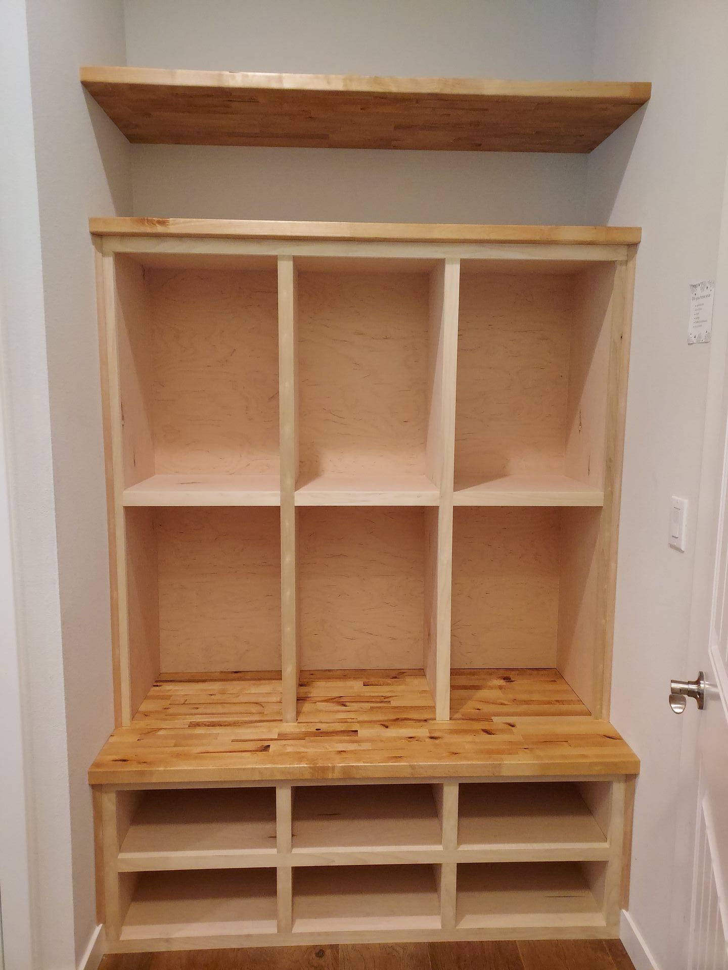 A wooden shelf with shelves and a bench in a closet.