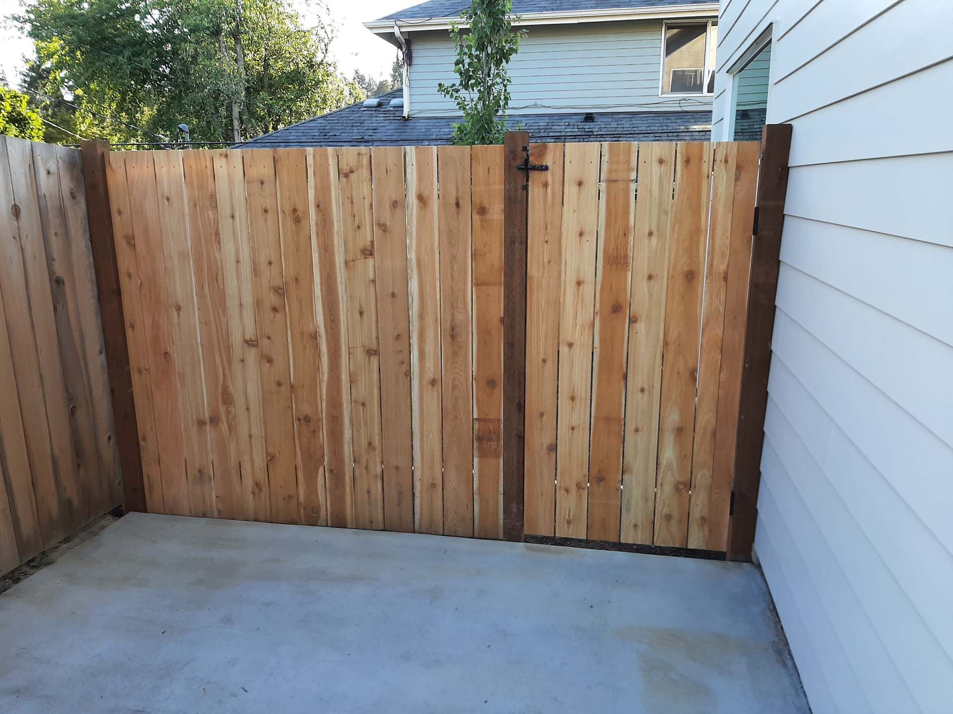 A wooden fence with a gate in the backyard of a house