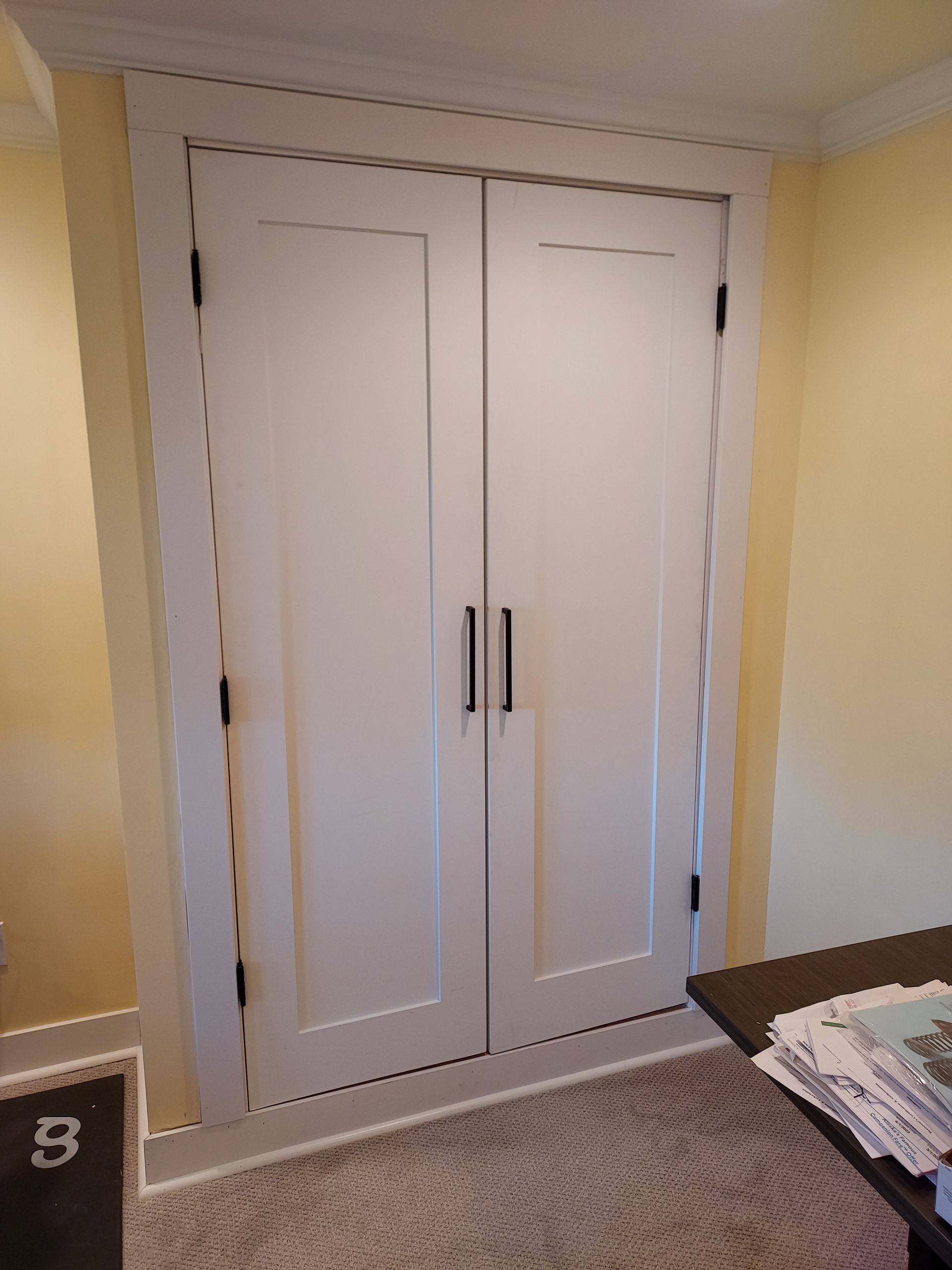 A room with two white doors and a table.