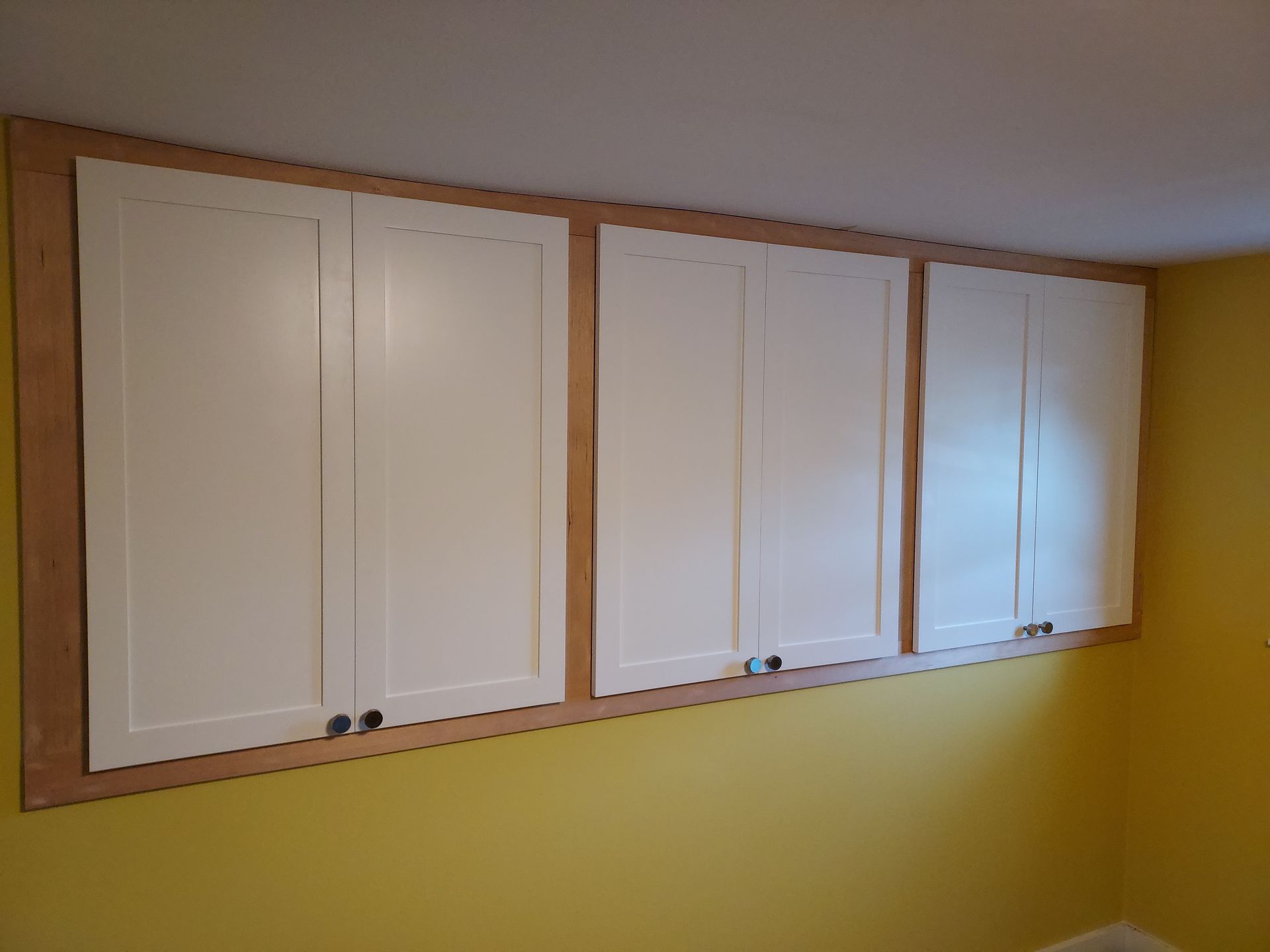 A room with yellow walls and white cabinets