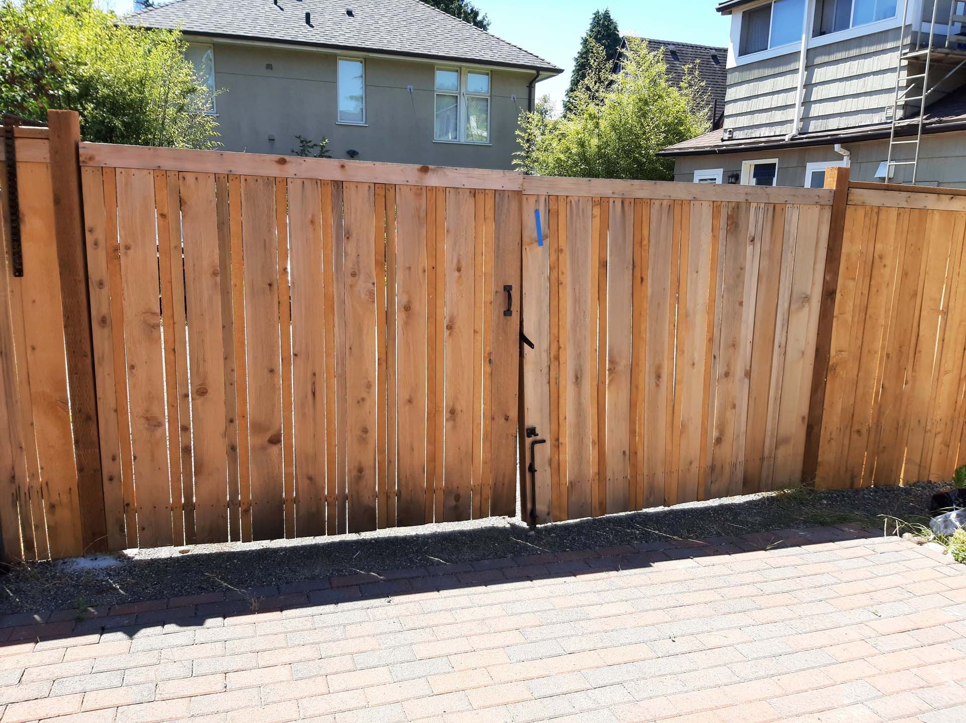A wooden fence with a gate in front of a house.