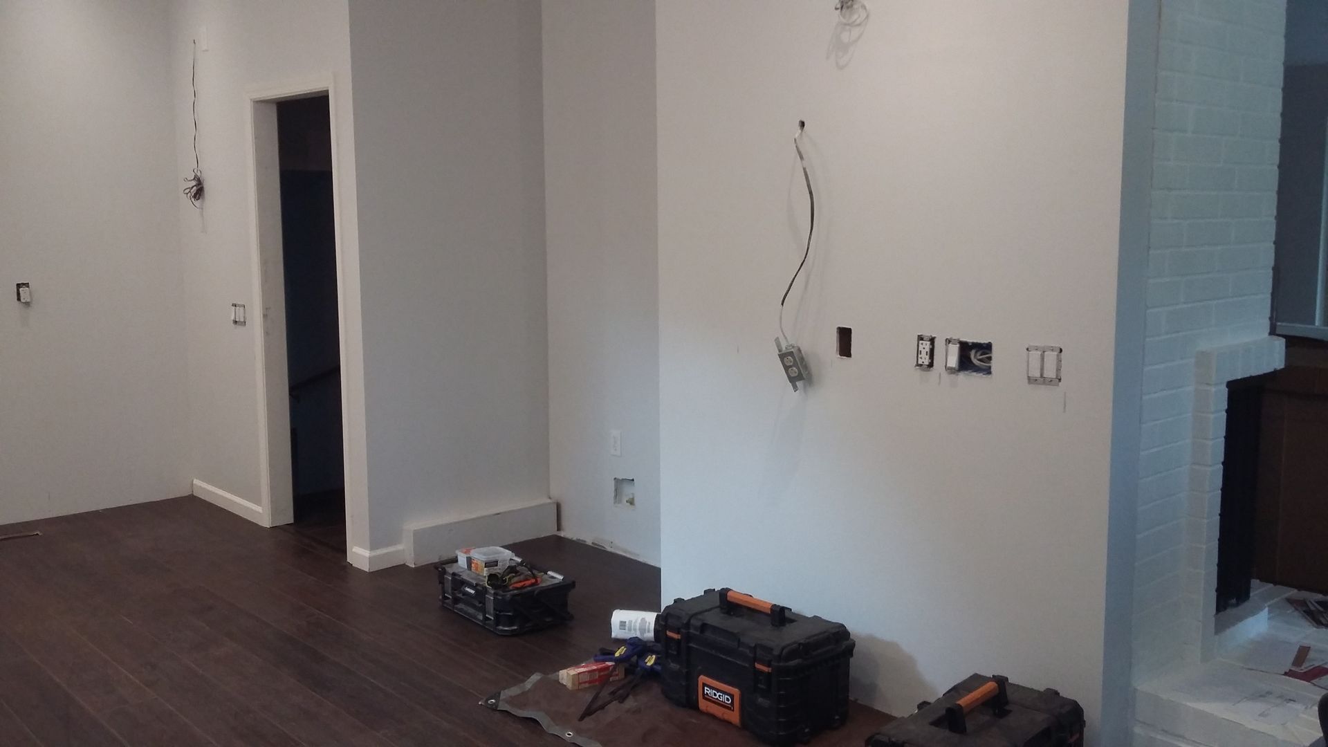 A living room with a wooden floor and a toolbox on the floor.