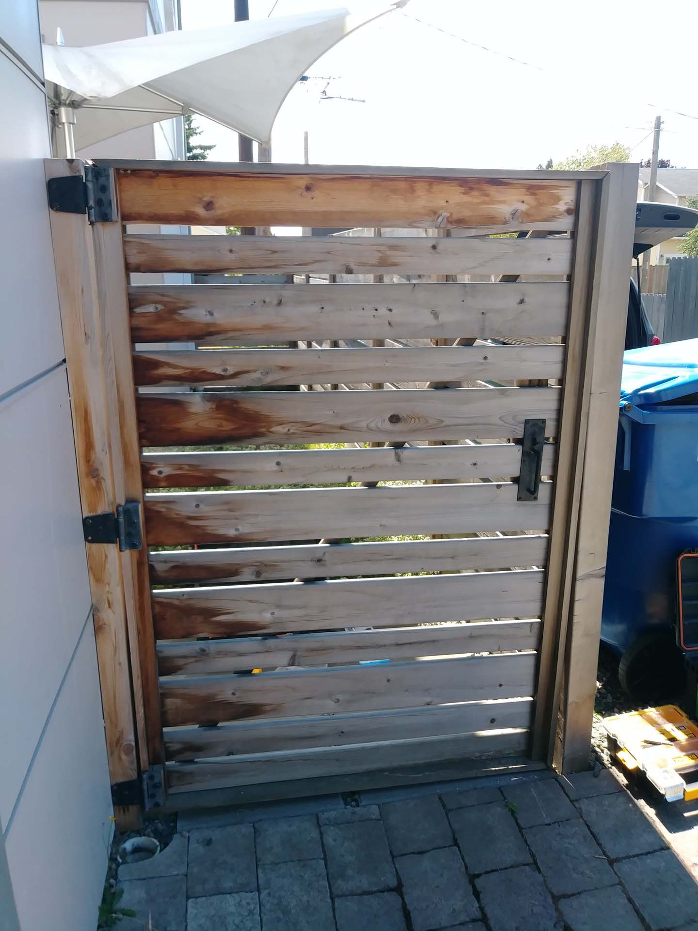 A wooden gate is sitting on a brick sidewalk next to a building.