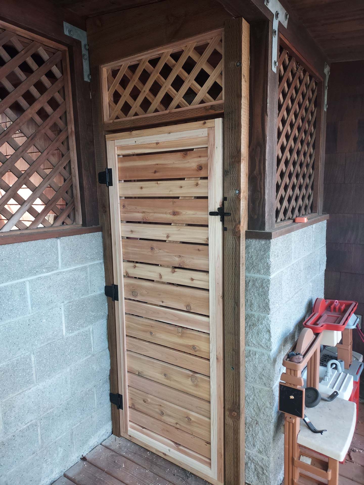 A wooden door is sitting on a wooden deck next to a brick wall.