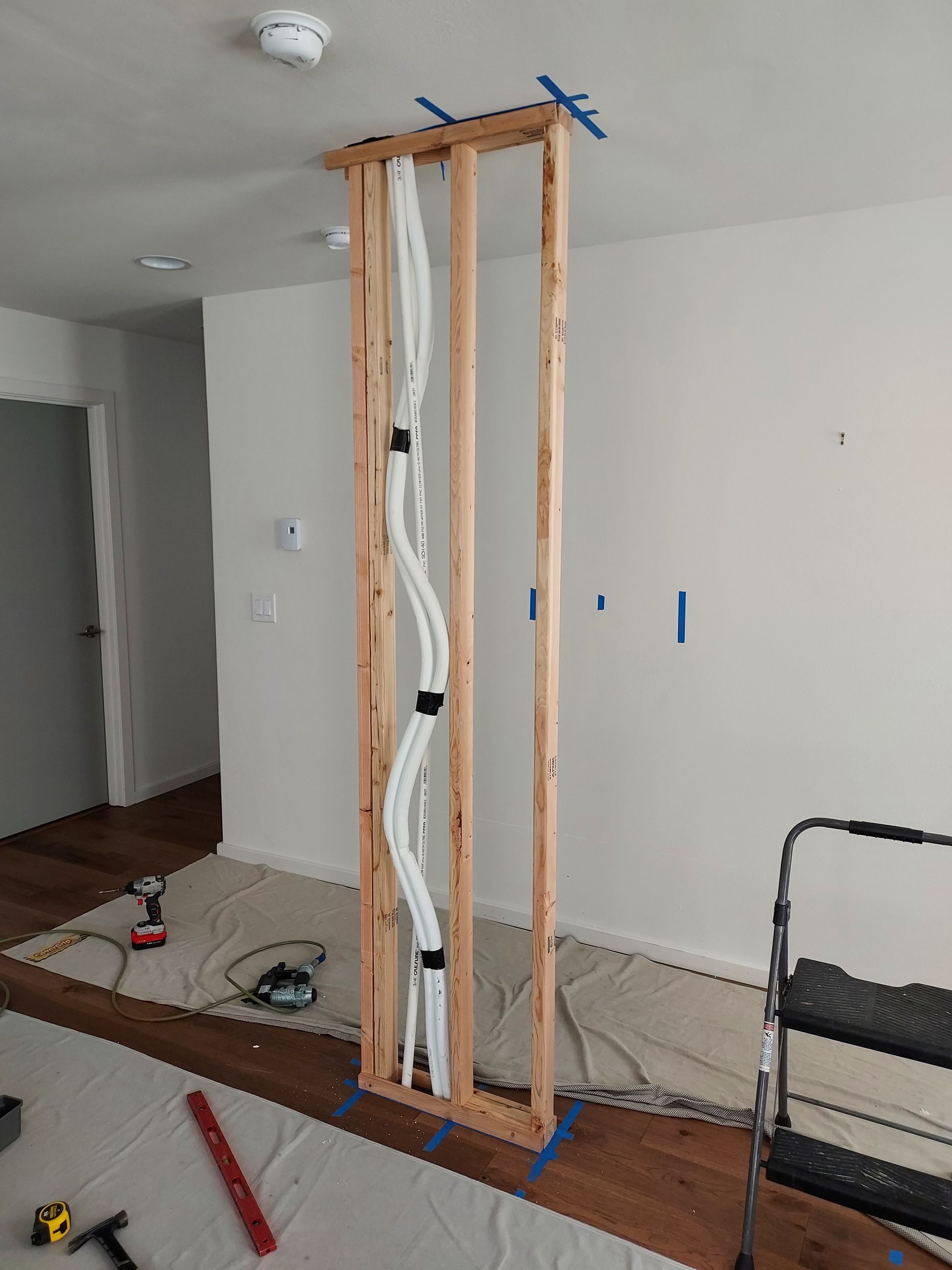 A wooden frame with pipes coming out of it is being built in a room.