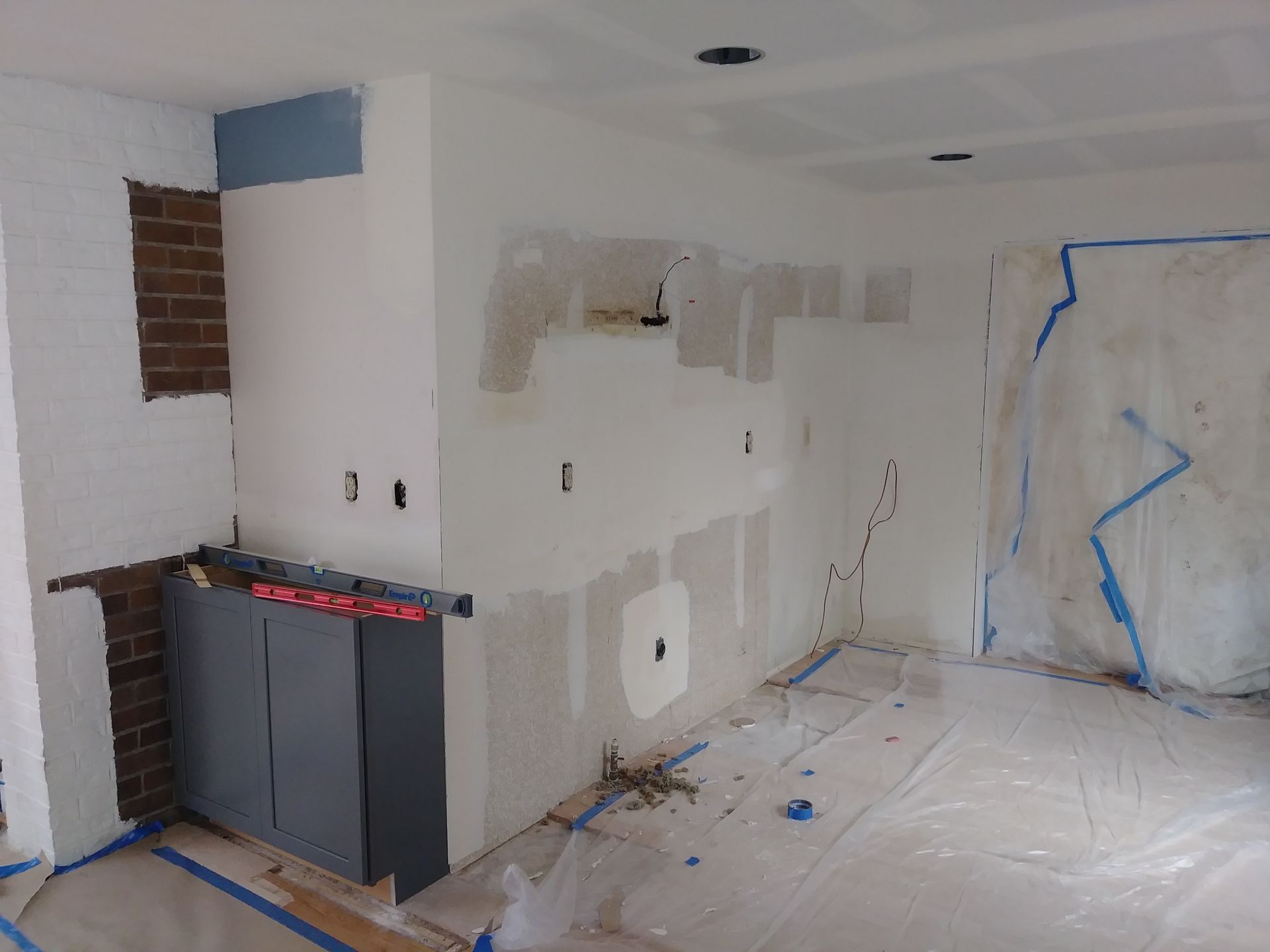 A room with white walls and blue tape on the floor.