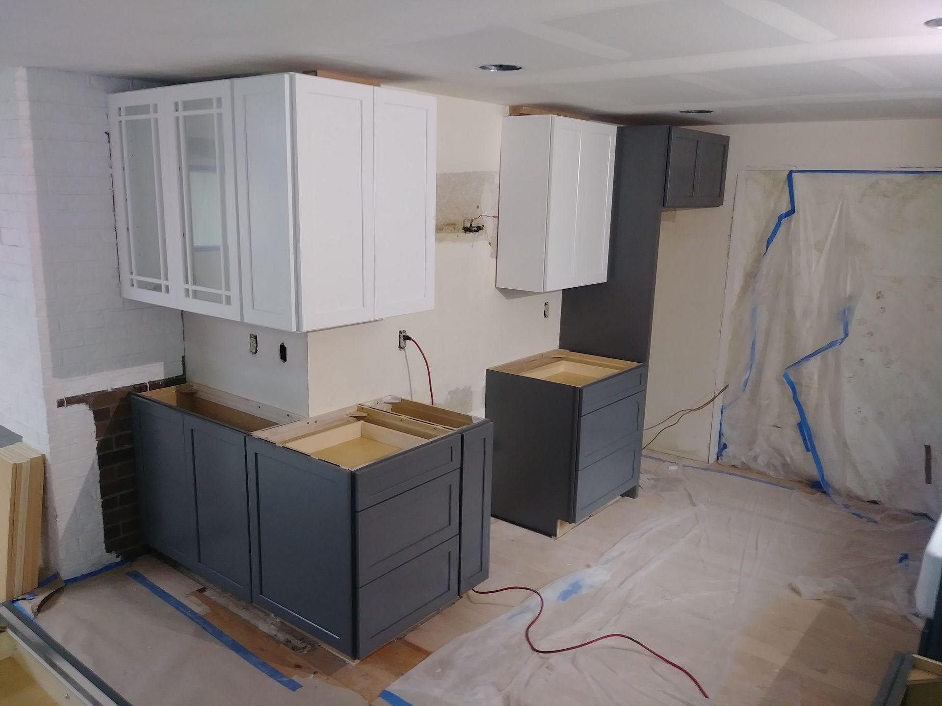 A kitchen under construction with white cabinets and gray cabinets