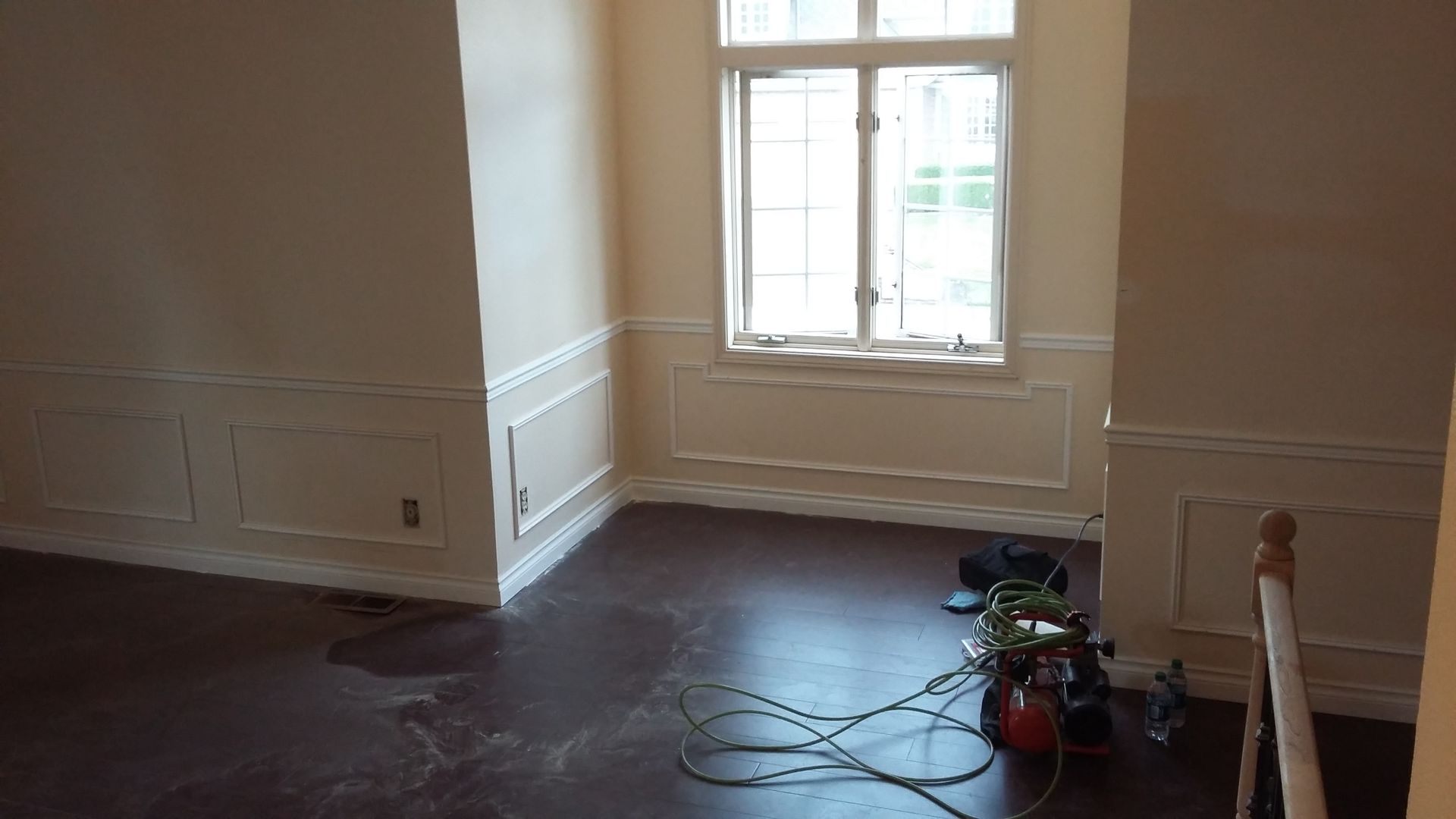 An empty room with a window and a vacuum cleaner on the floor