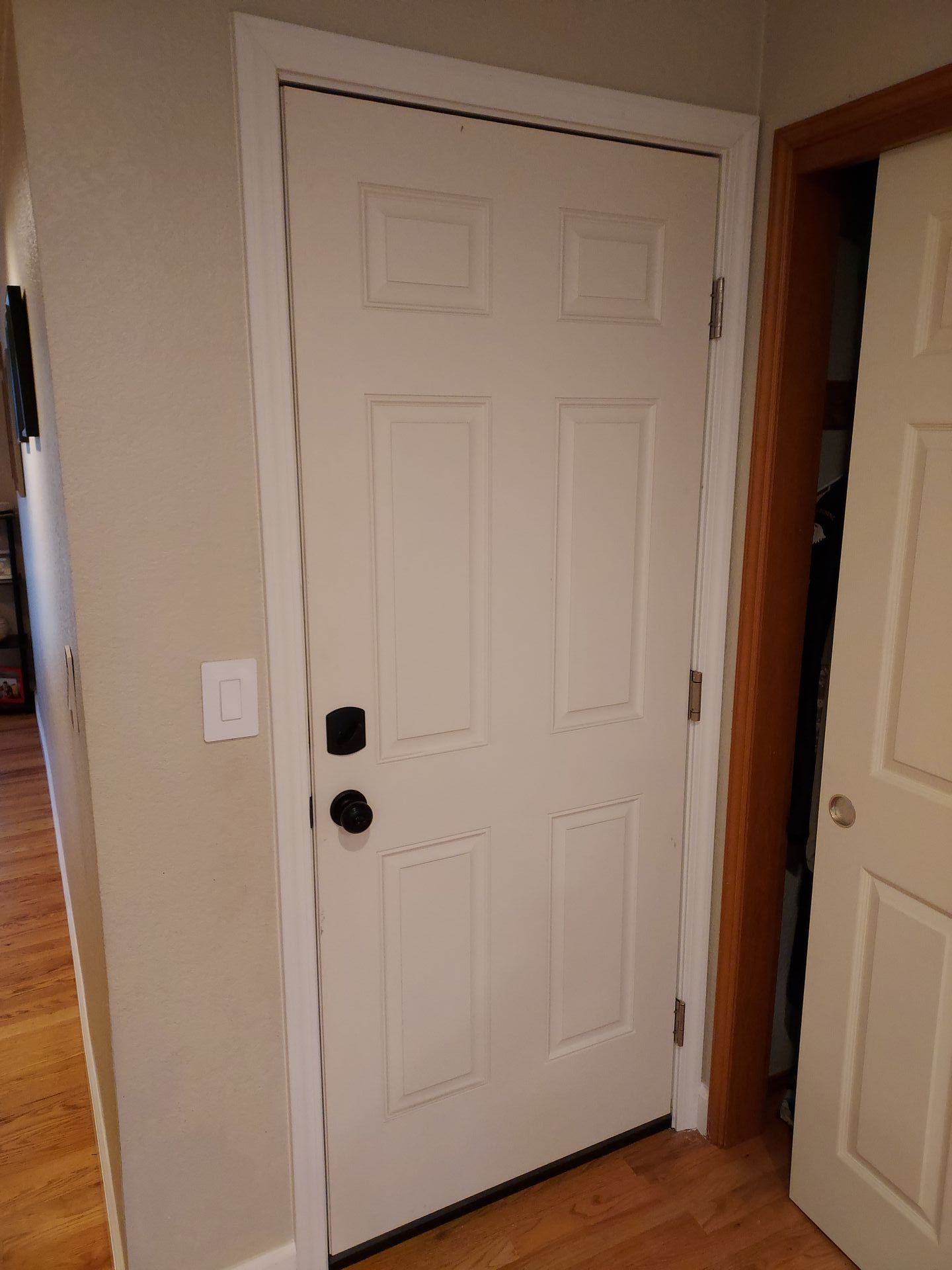 A white door with a black handle is in a hallway.
