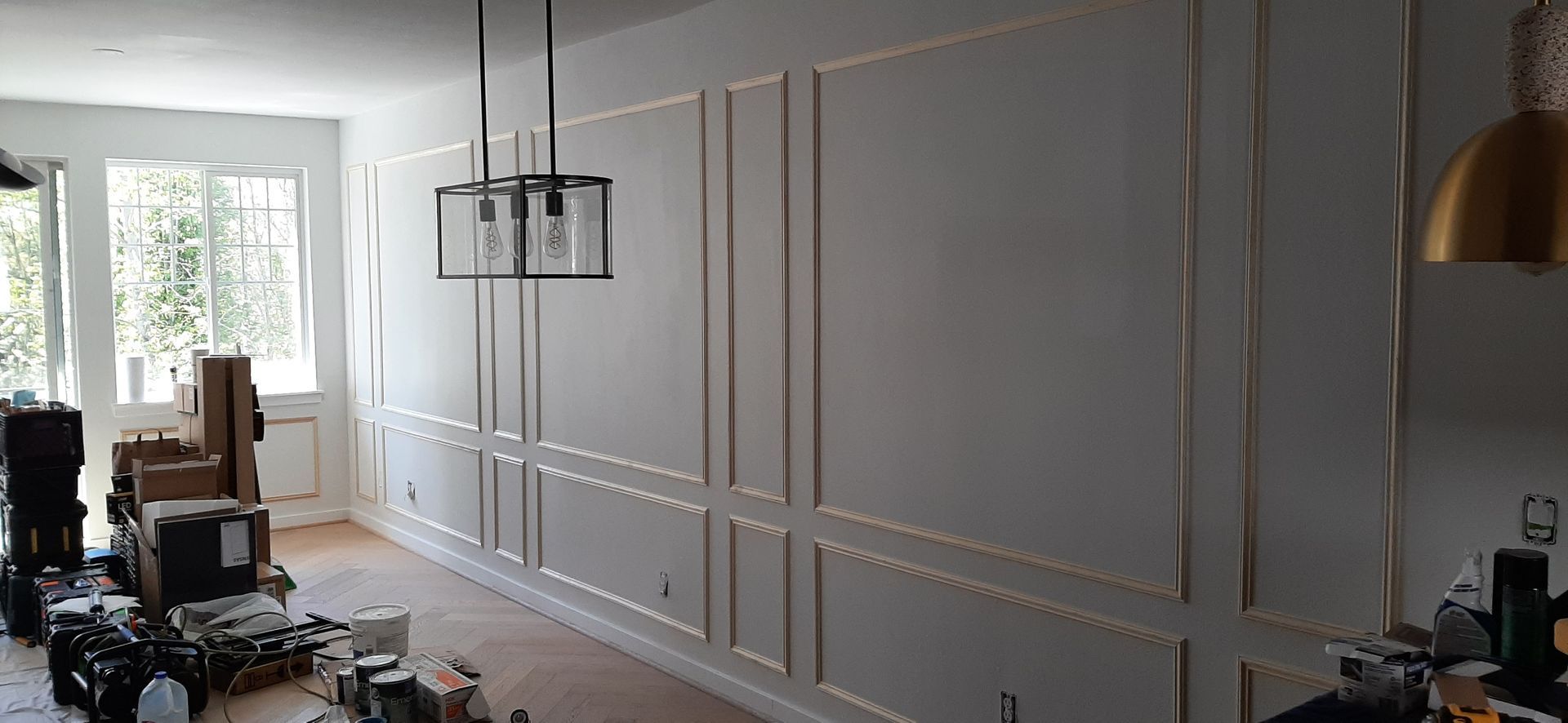 A living room with a large wall and a chandelier hanging from the ceiling.