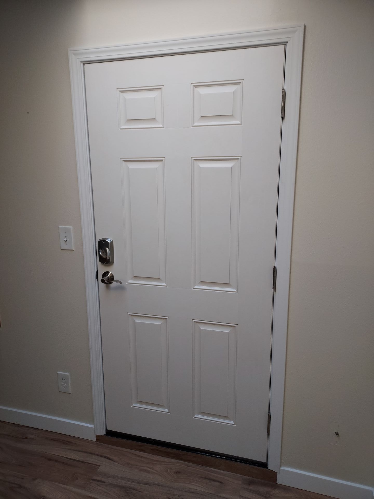 A white door is sitting in a room next to a wall.
