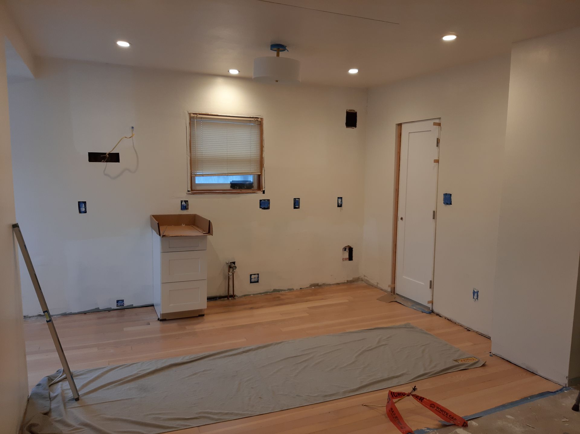A room with hardwood floors and white walls is being remodeled.