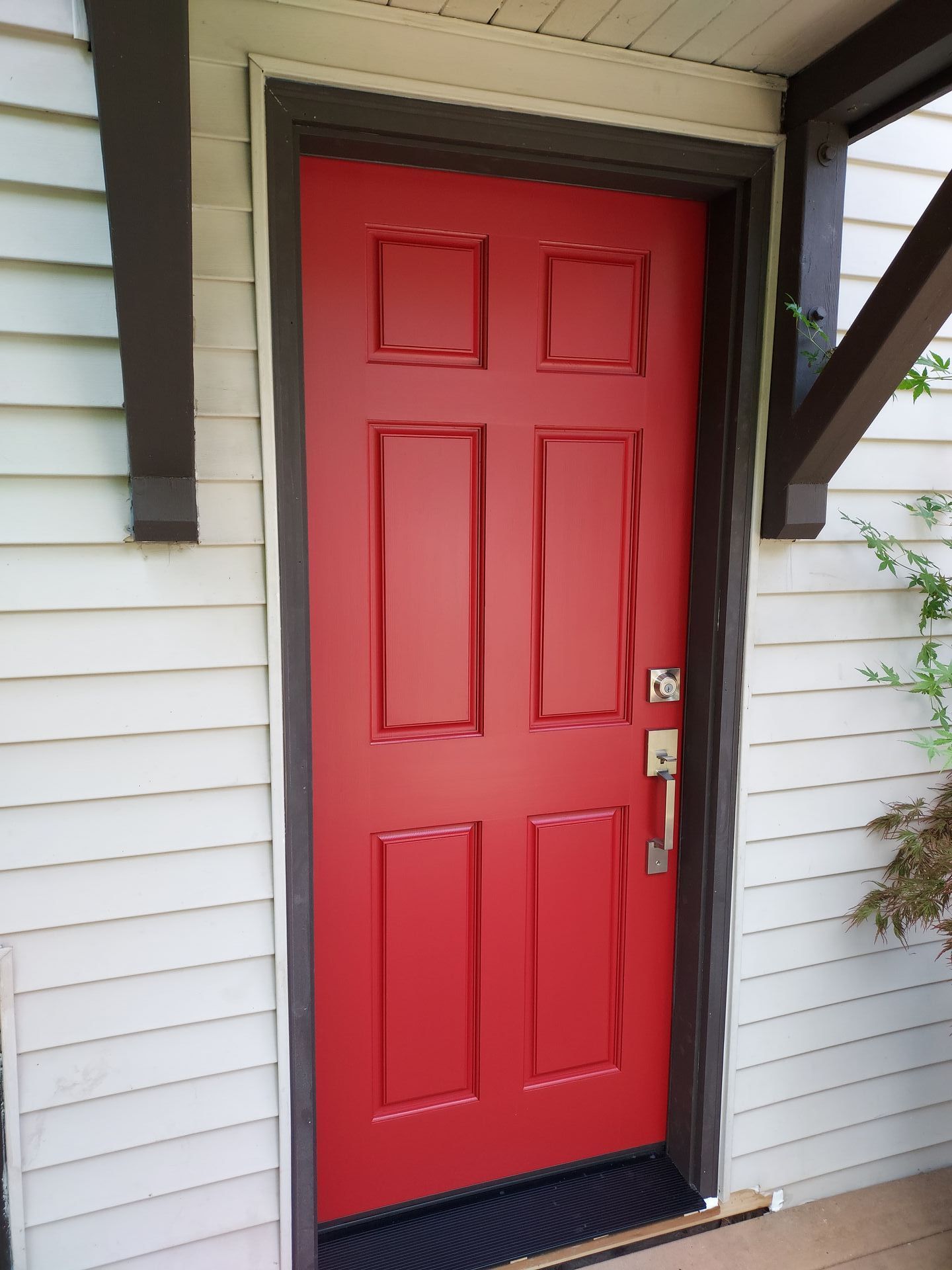 A red door is on the side of a white house