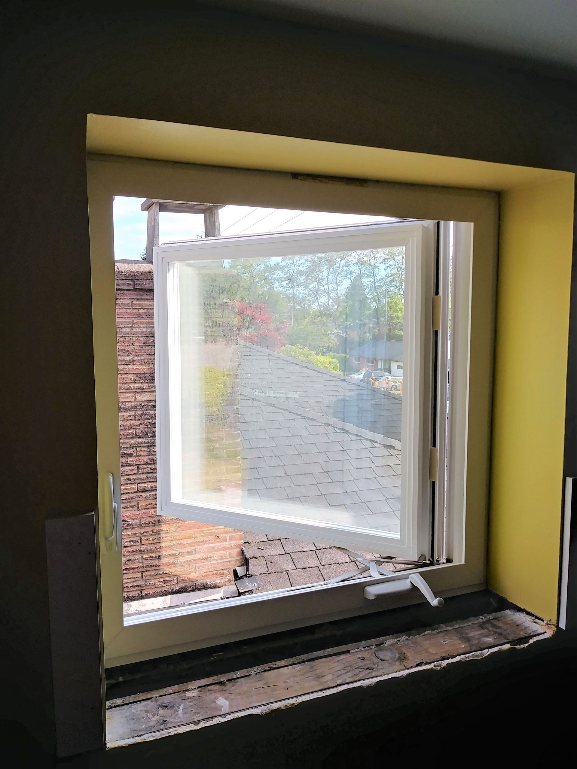 A window is open in a room with a yellow wall.