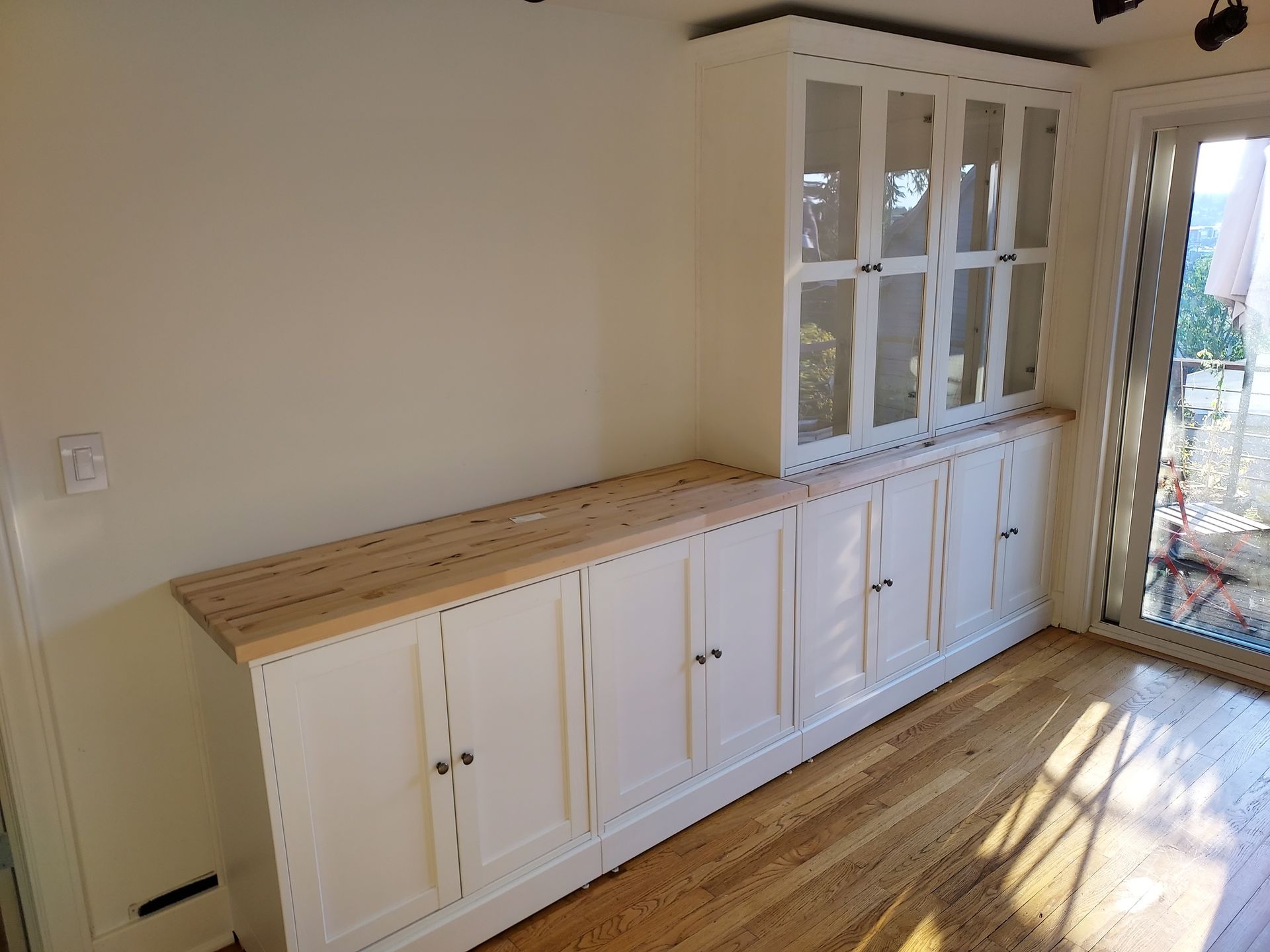 A room with a lot of cabinets and a sliding glass door.