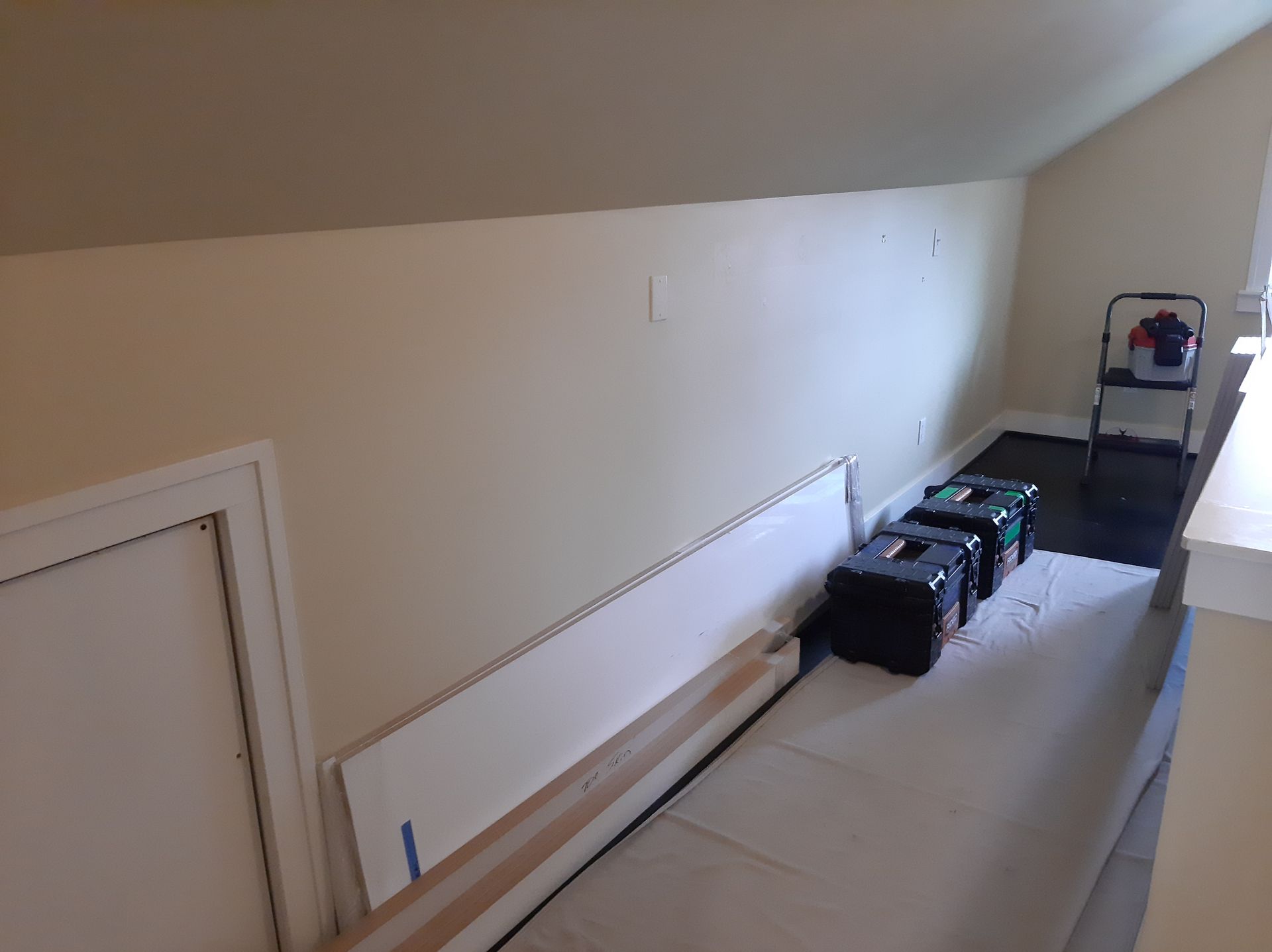 A room with a ladder and boxes on the floor.
