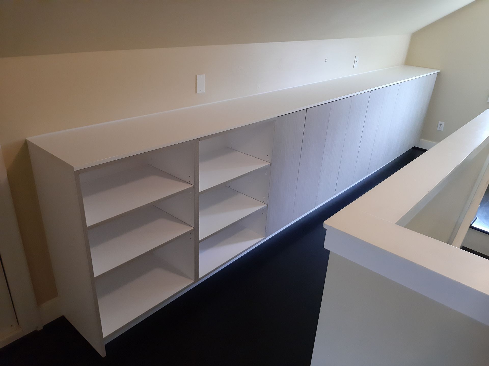 A room with a staircase and a long white shelf