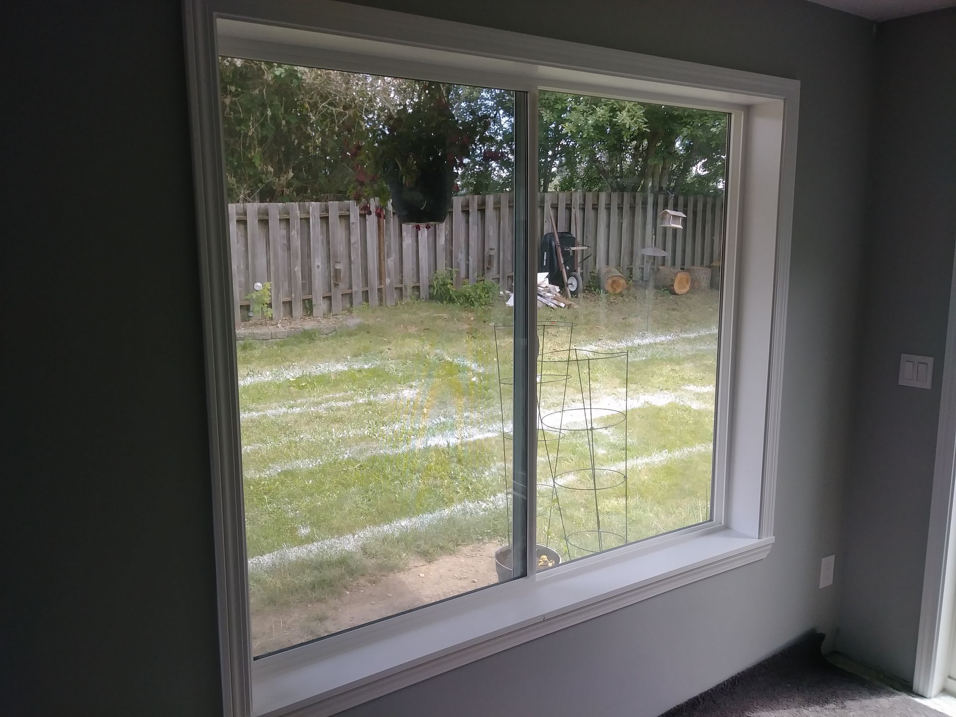 A large window in a room with a fence in the background.