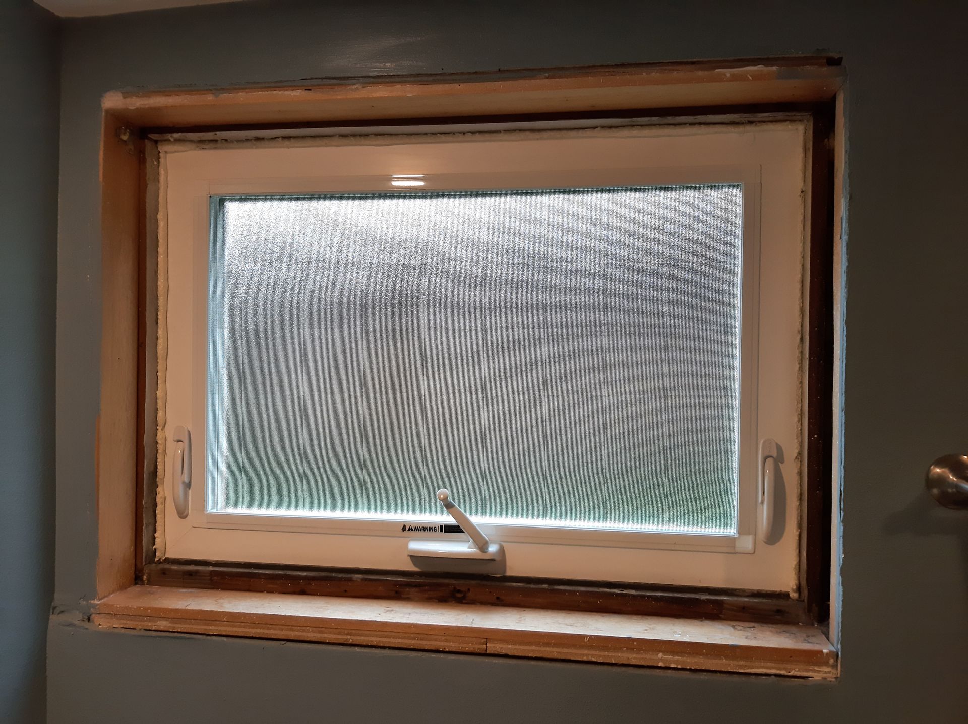 A window is being installed in a room with a gray wall.