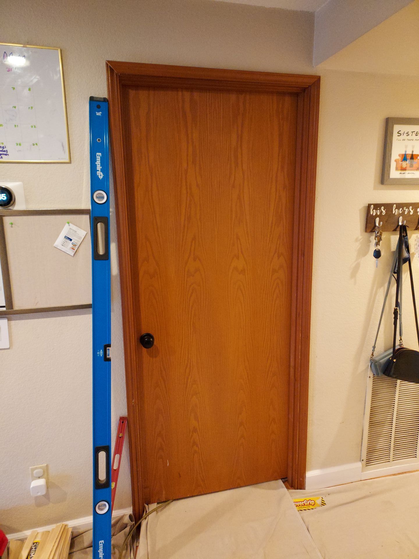 A blue level is sitting next to a wooden door in a room.