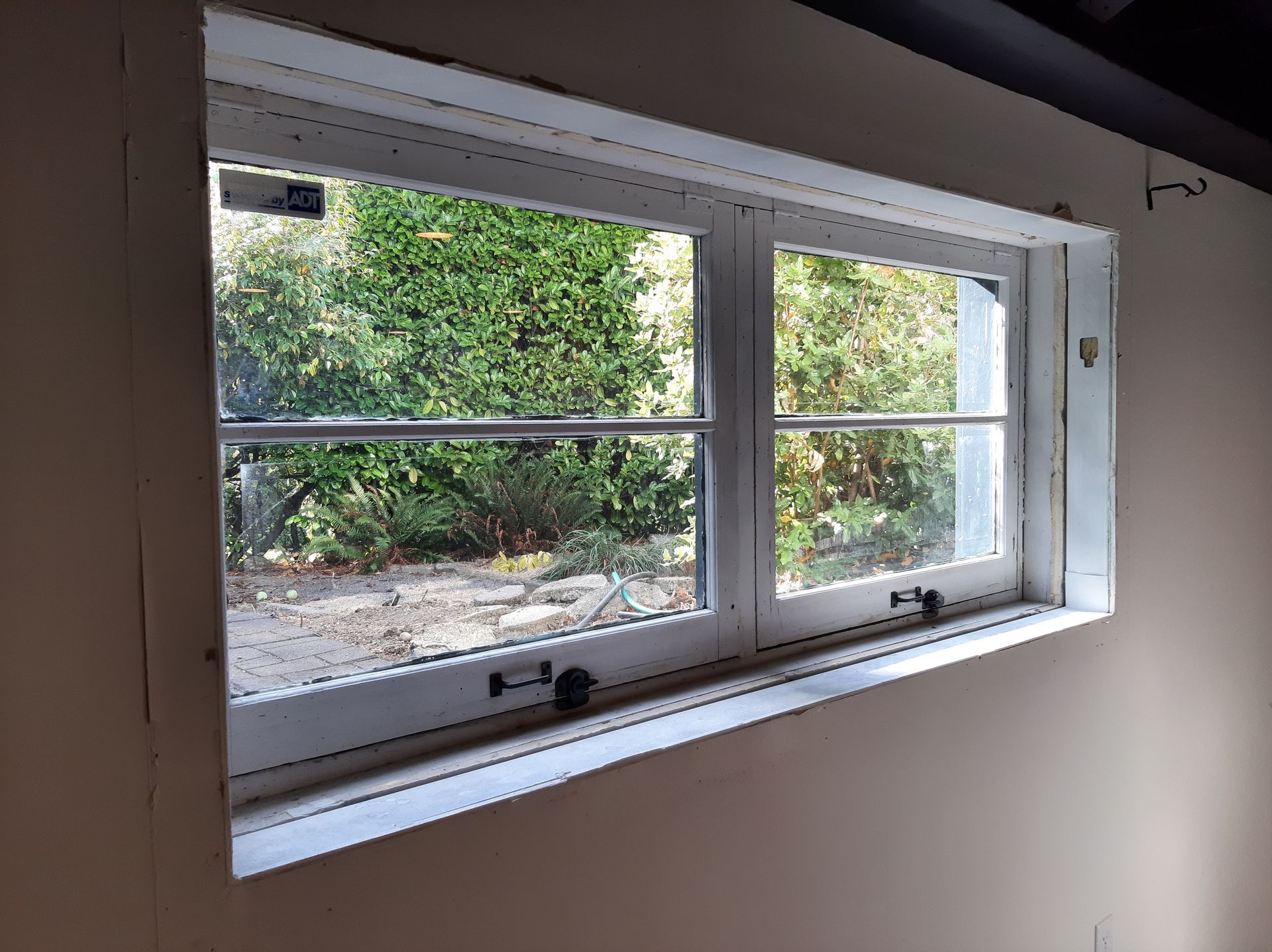 A white window with a view of trees in a room.