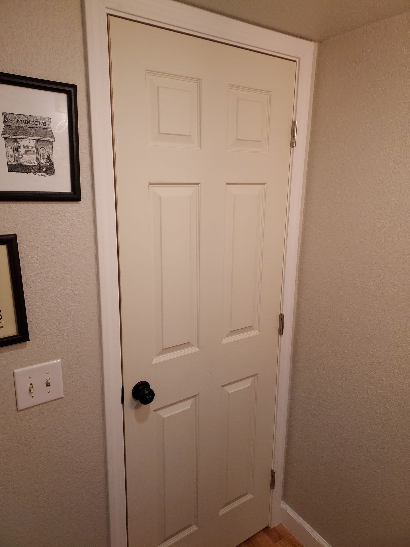 A white door with a black knob is in a room.