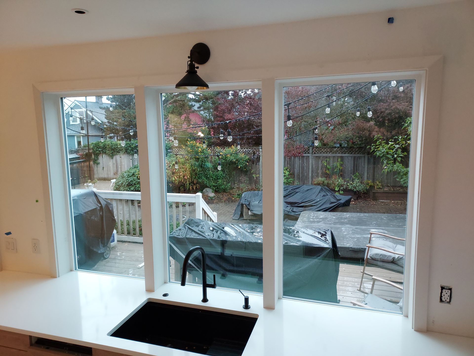 A kitchen with a sink and a view of a backyard