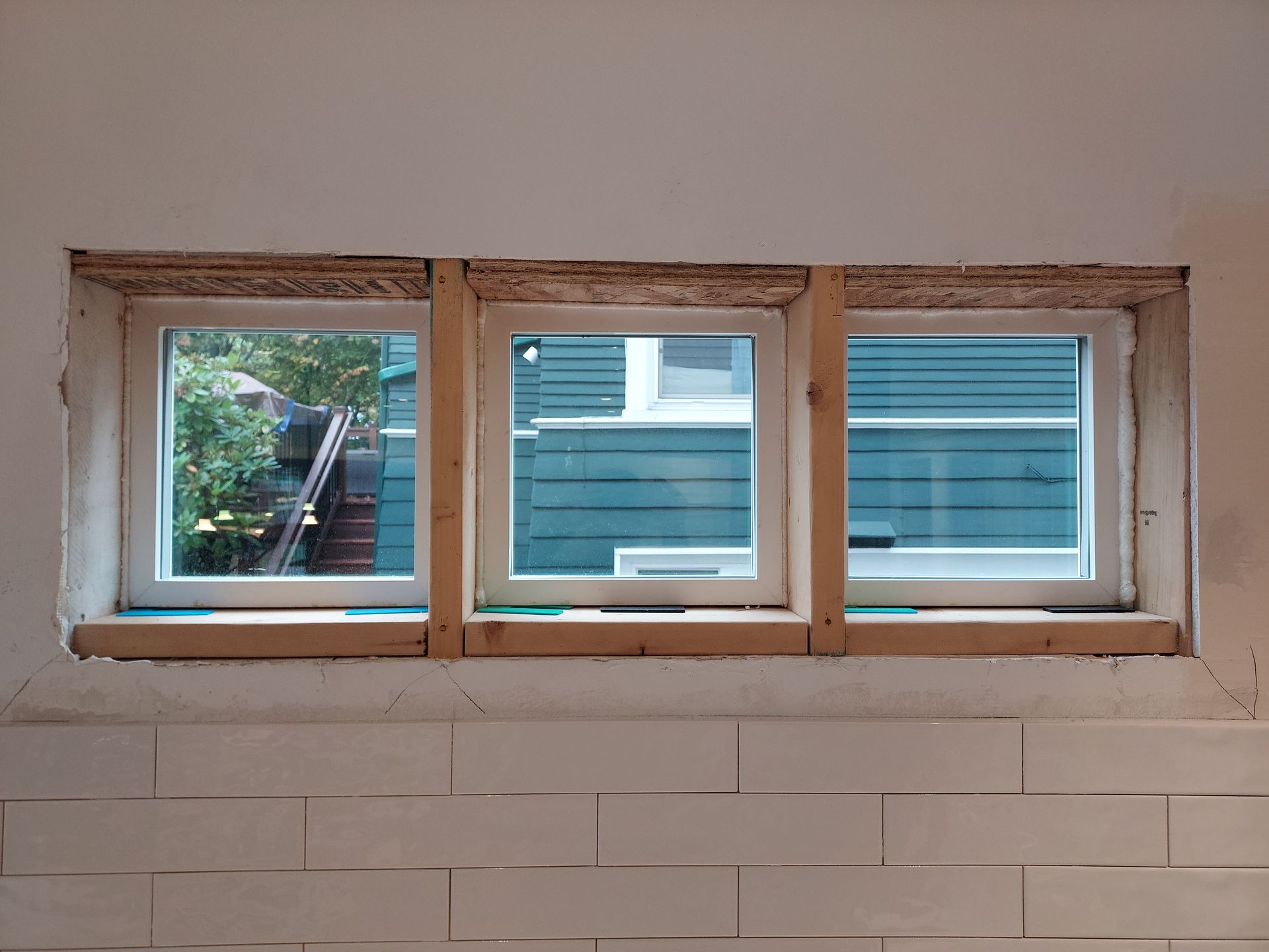 Three windows are being installed on a white brick wall