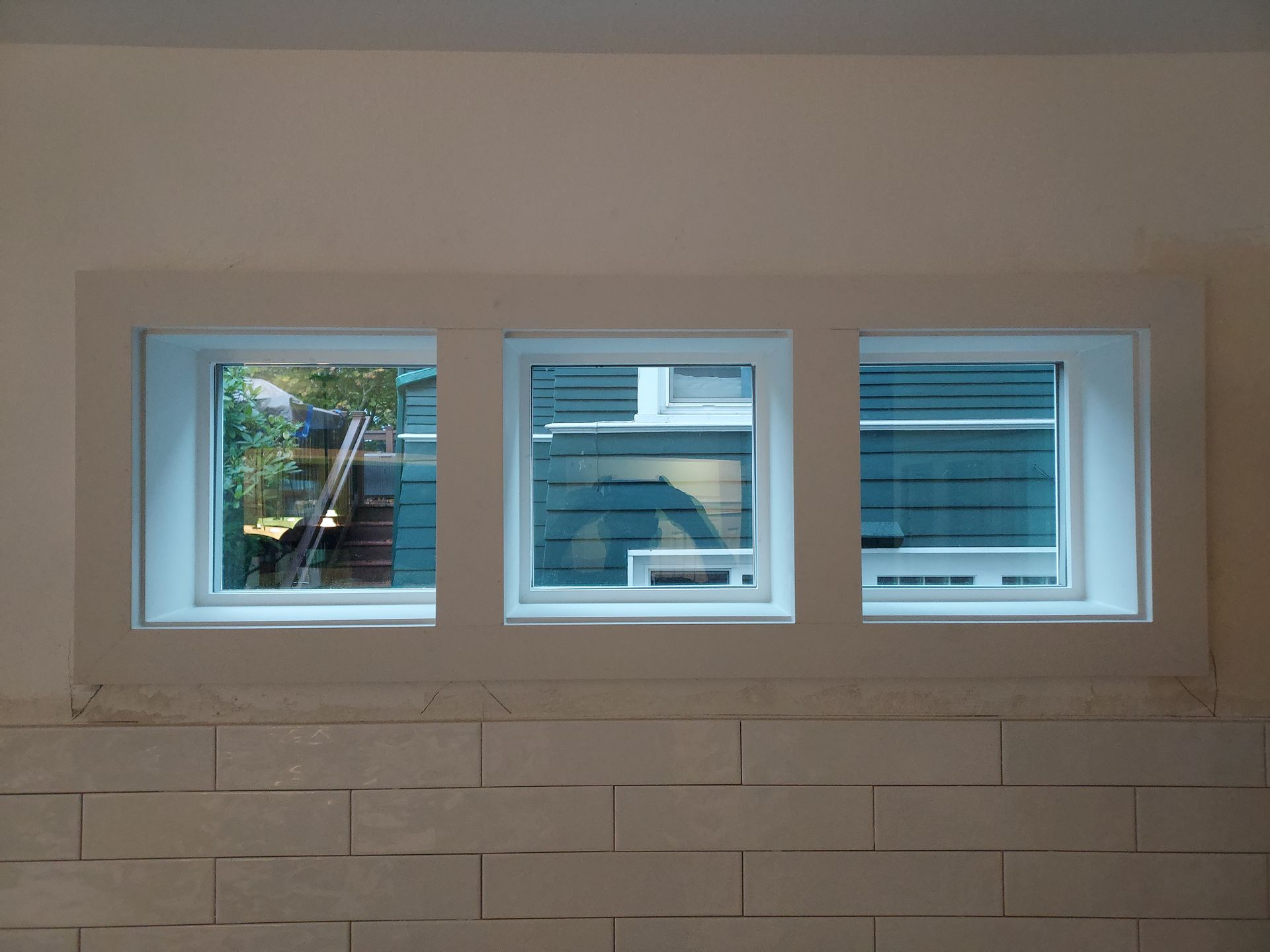 Three windows in a room with a brick wall