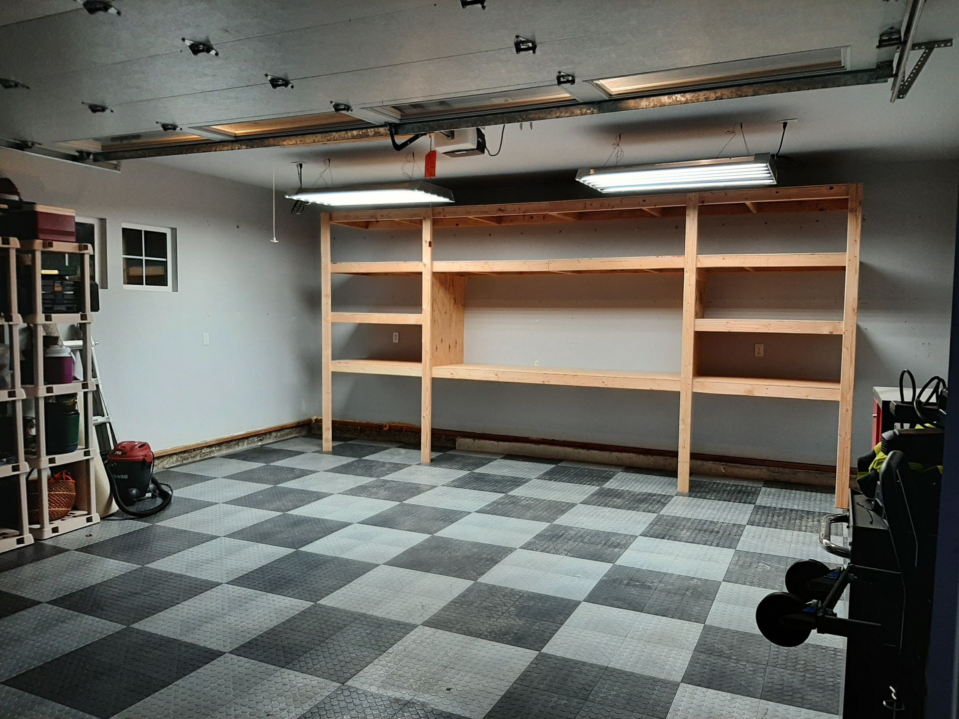 An empty garage with a checkered floor and shelves.