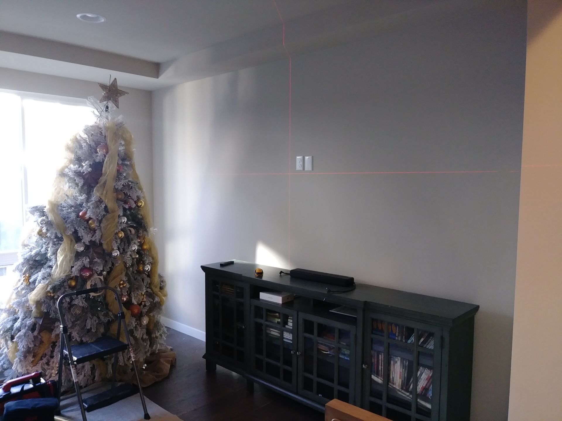 A living room with a christmas tree and a television stand.