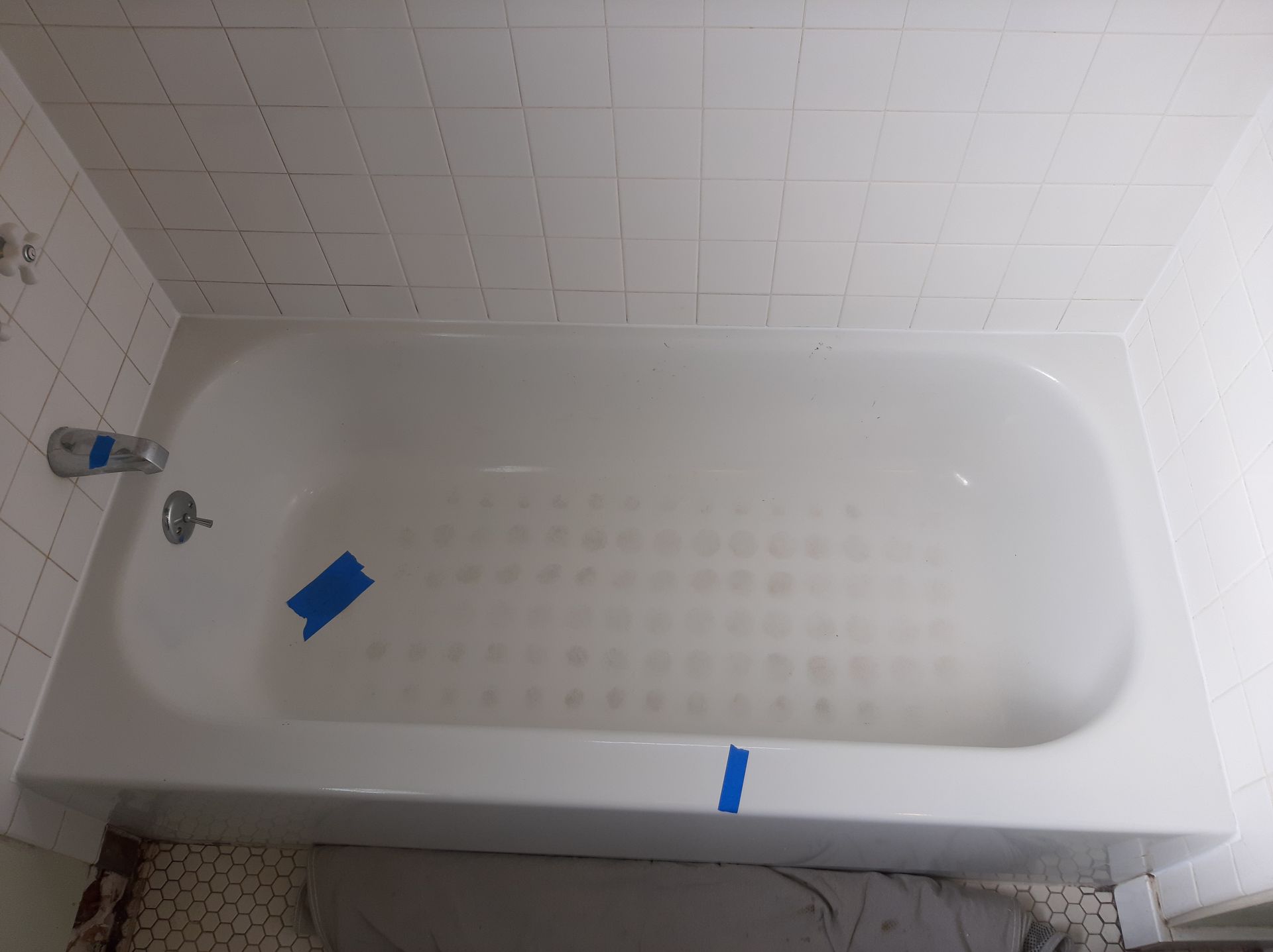 A bathtub is taped to the floor in a bathroom.