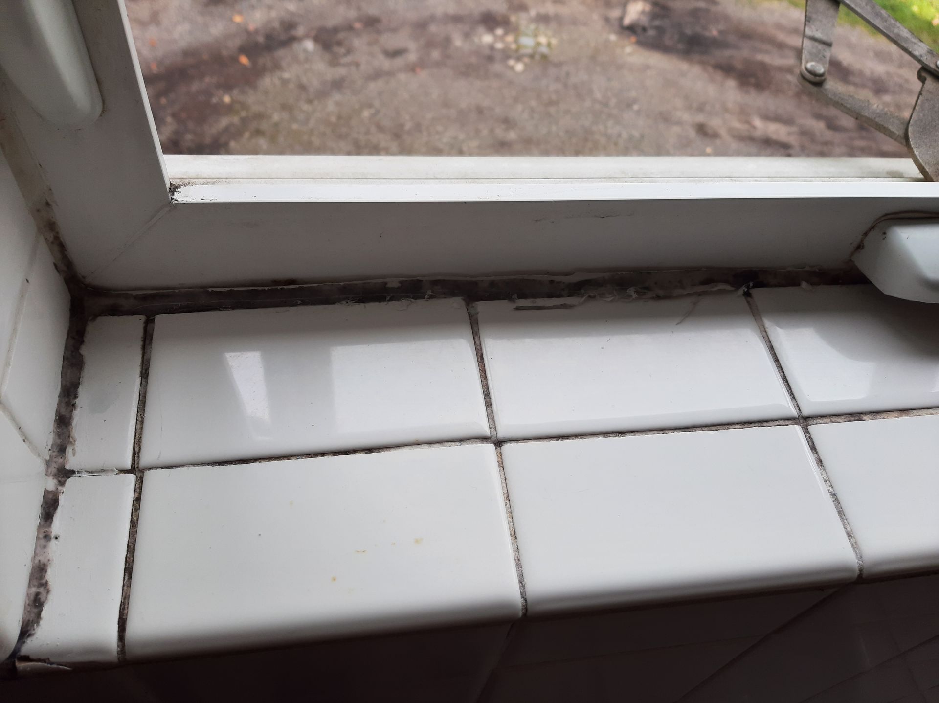 A window sill with white tiles on it and a person standing in the background.