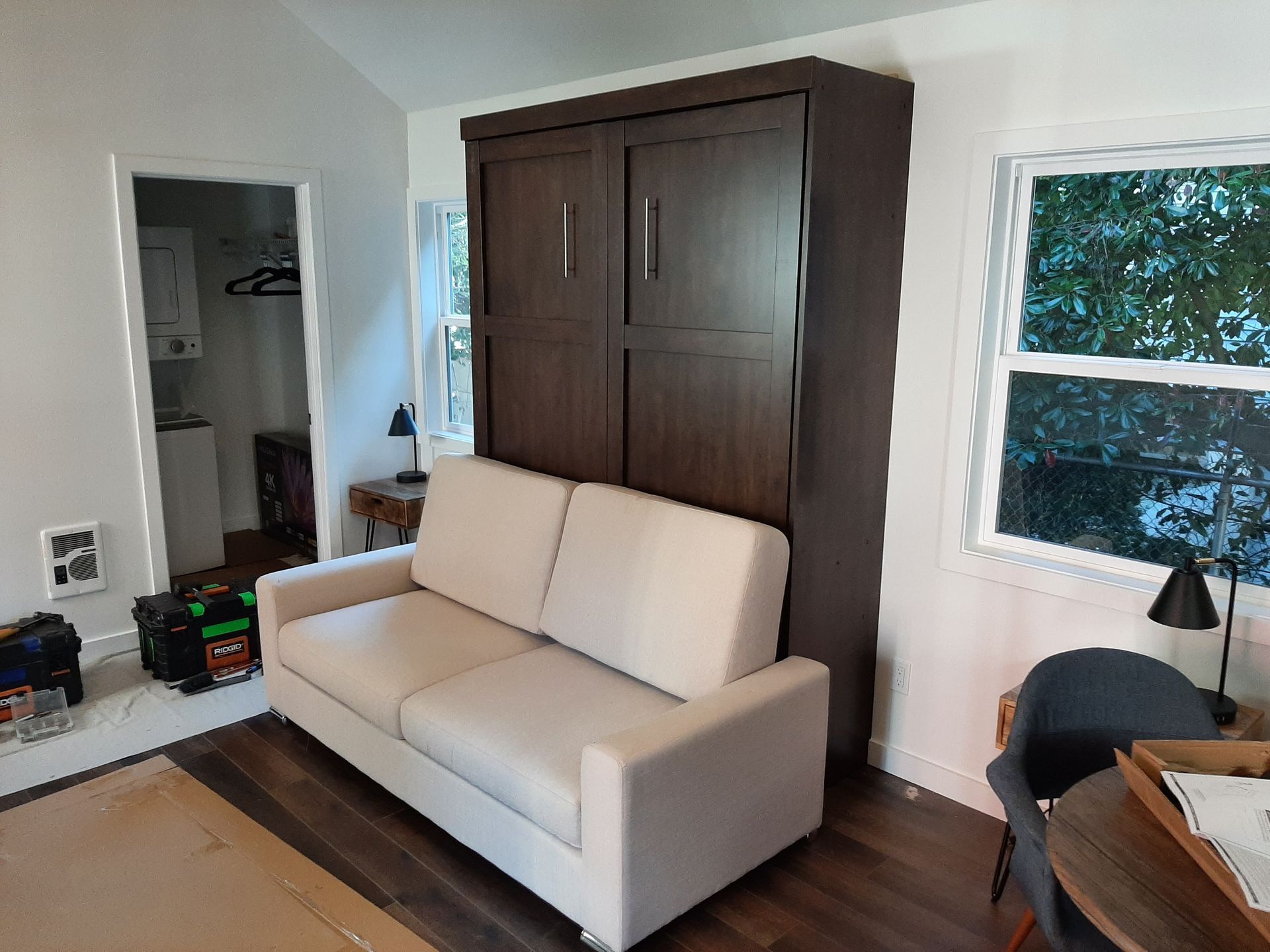 A couch is sitting in a living room next to a wall mounted bed.