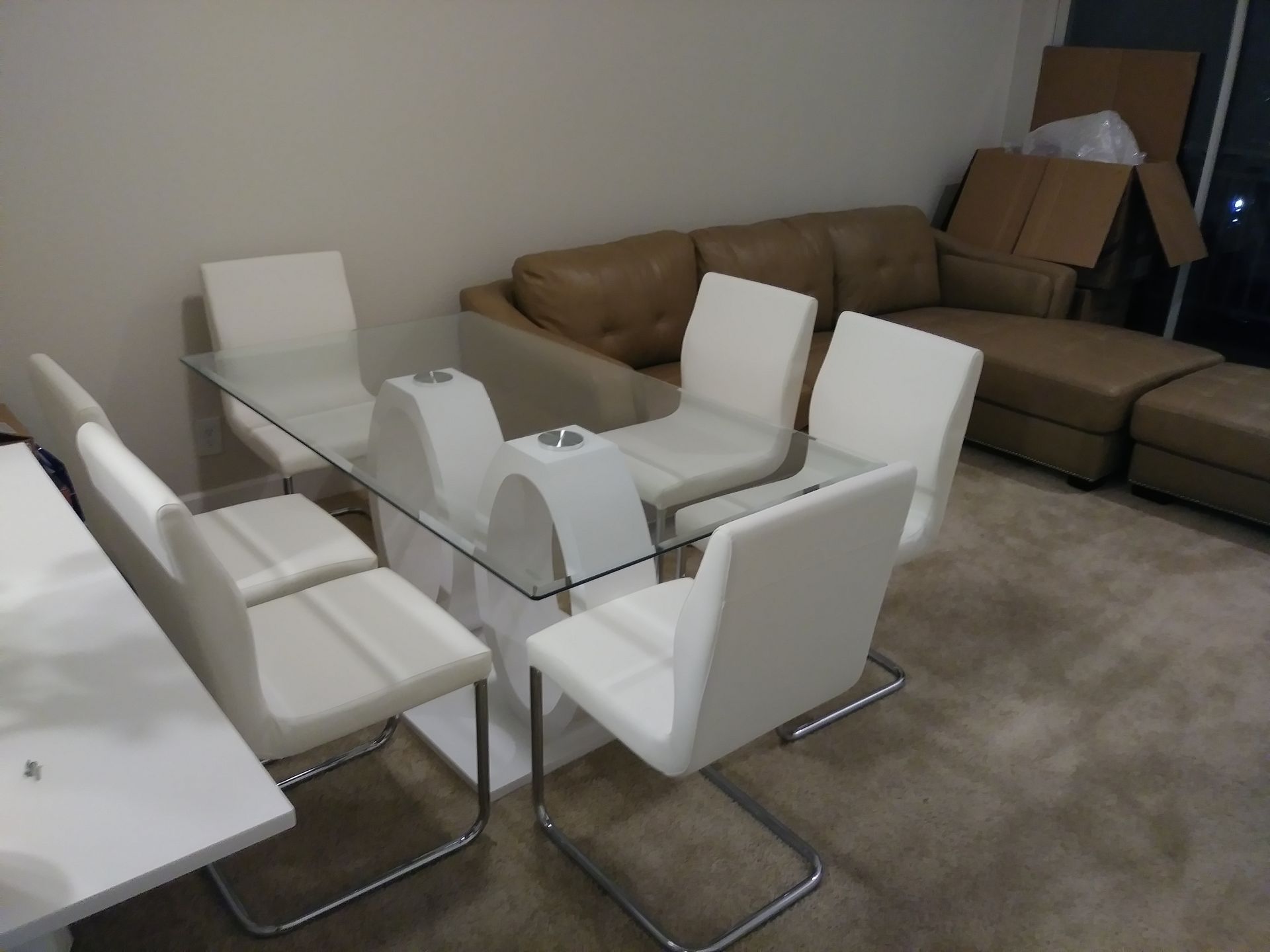 A living room with a glass table and white chairs